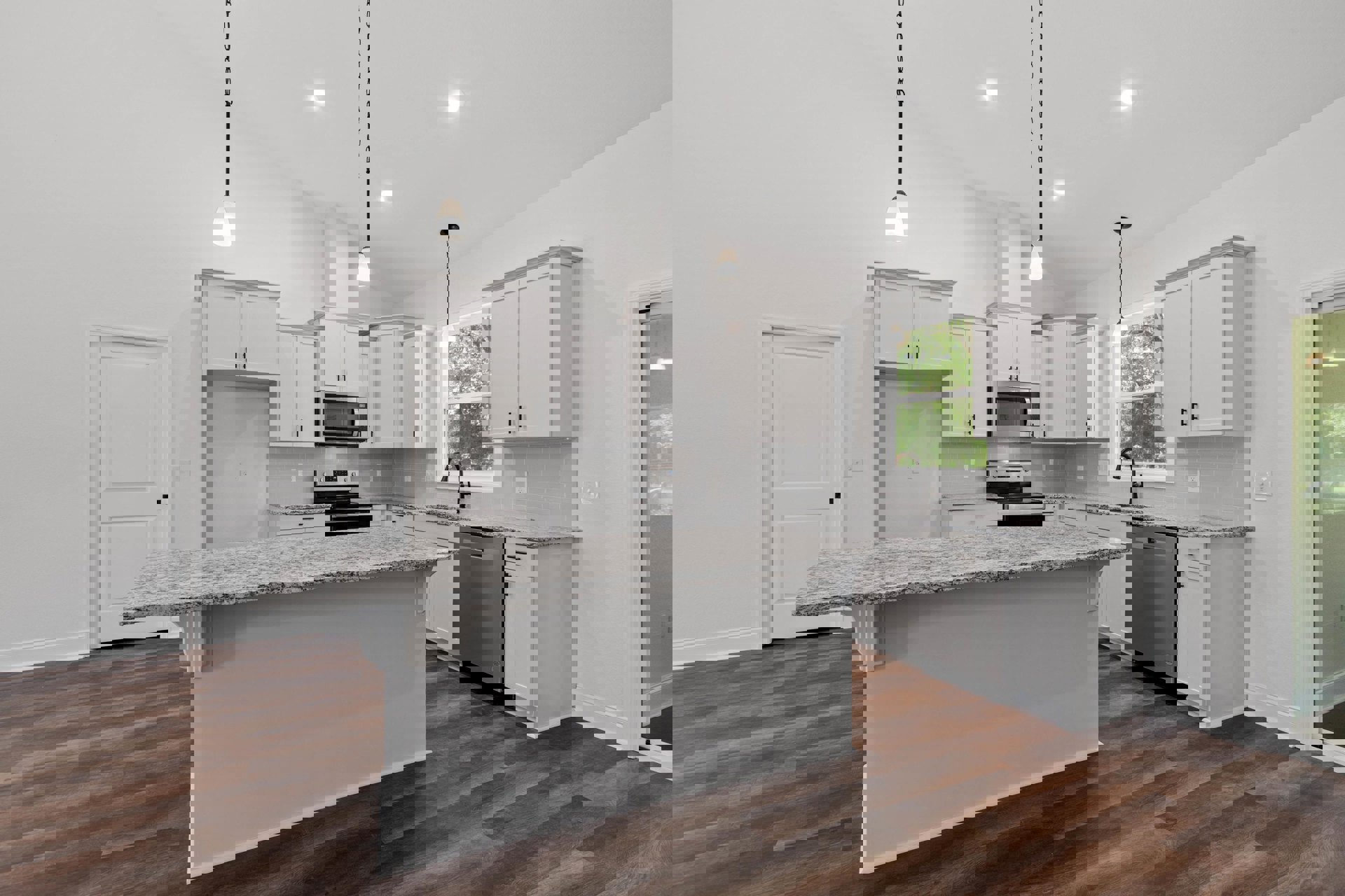 White kitchen cabinets, granite island with sink, stainless steel appliances including open microwave and dishwasher, light tile flooring, large window above counter, modern