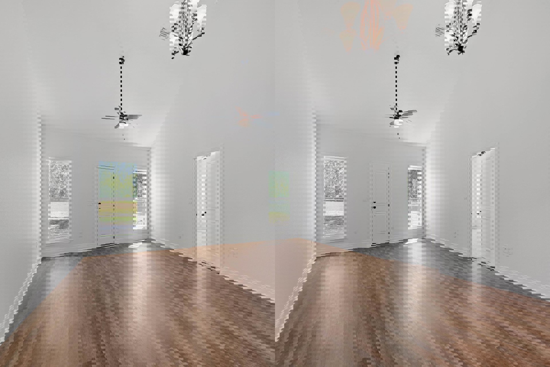 Spacious room with white plaster walls, wood laminate flooring, ceiling fan with light, white door featuring black hardware