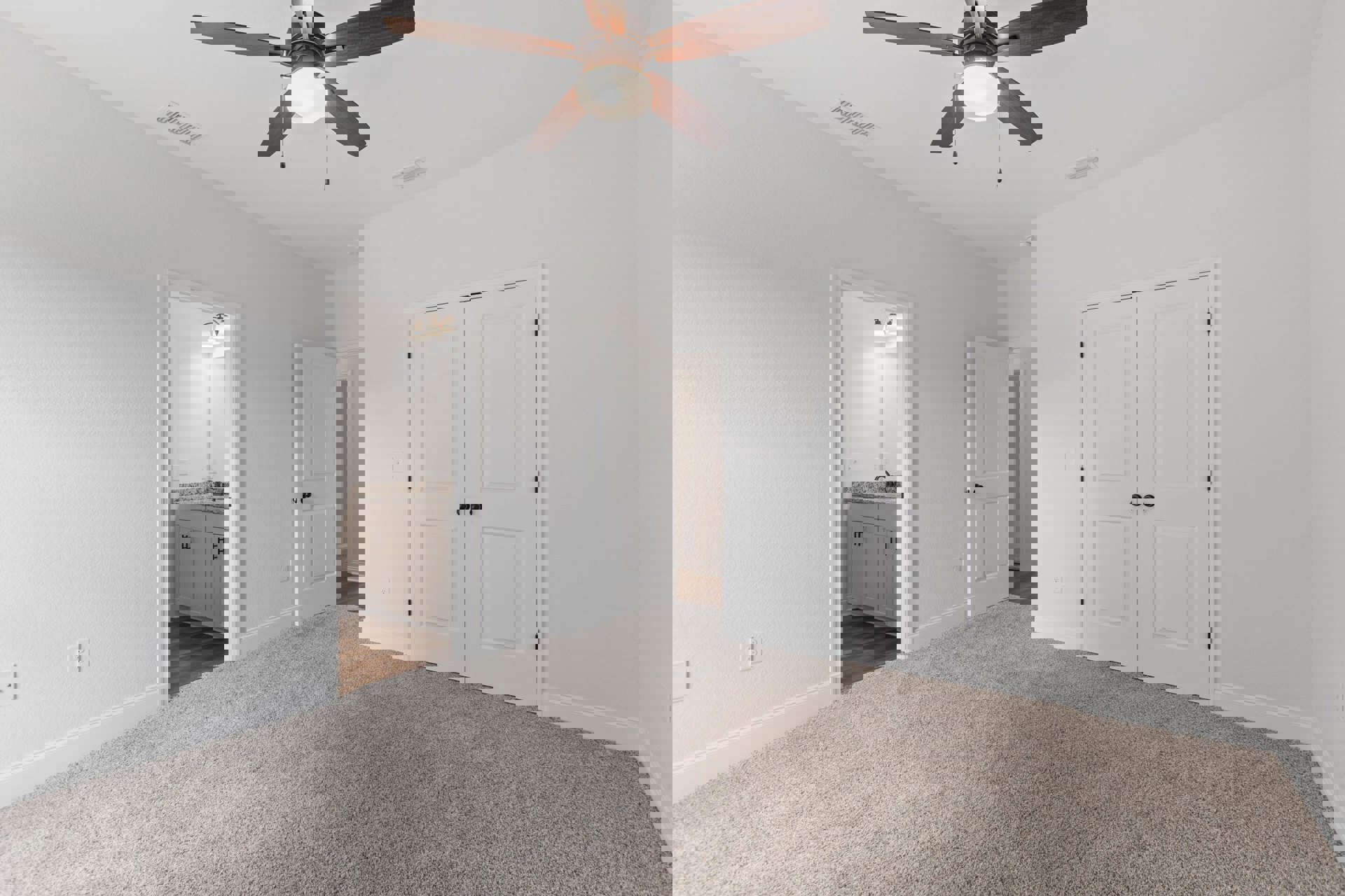 Carpeted room with white walls, ceiling fan with light fixture, two white doors featuring black knobs, and simple baseboard trim