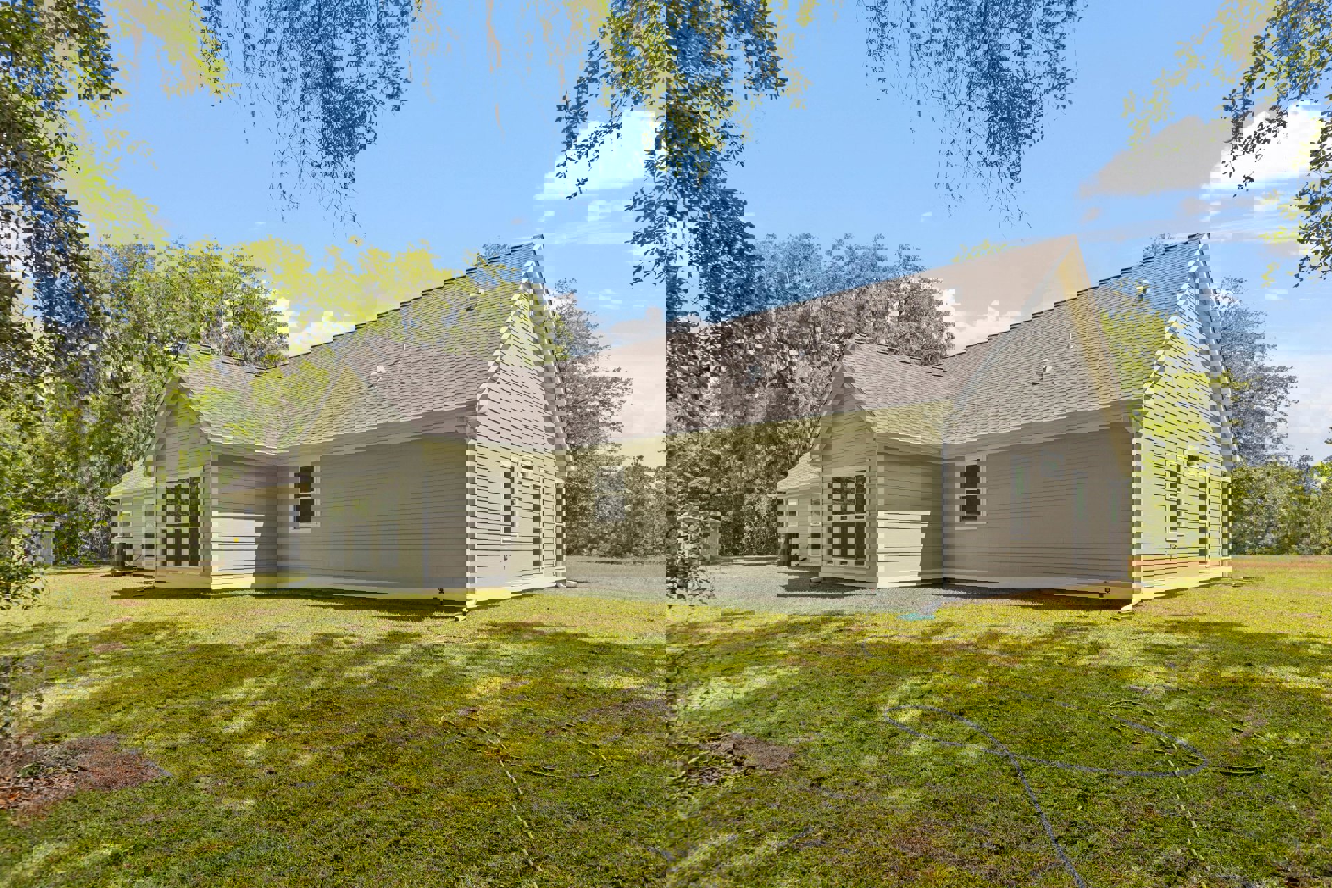 White farmhouse with gabled roof, large windows, and white trim, set on a green lawn with mature trees and Robert Frost Farm visible in the background