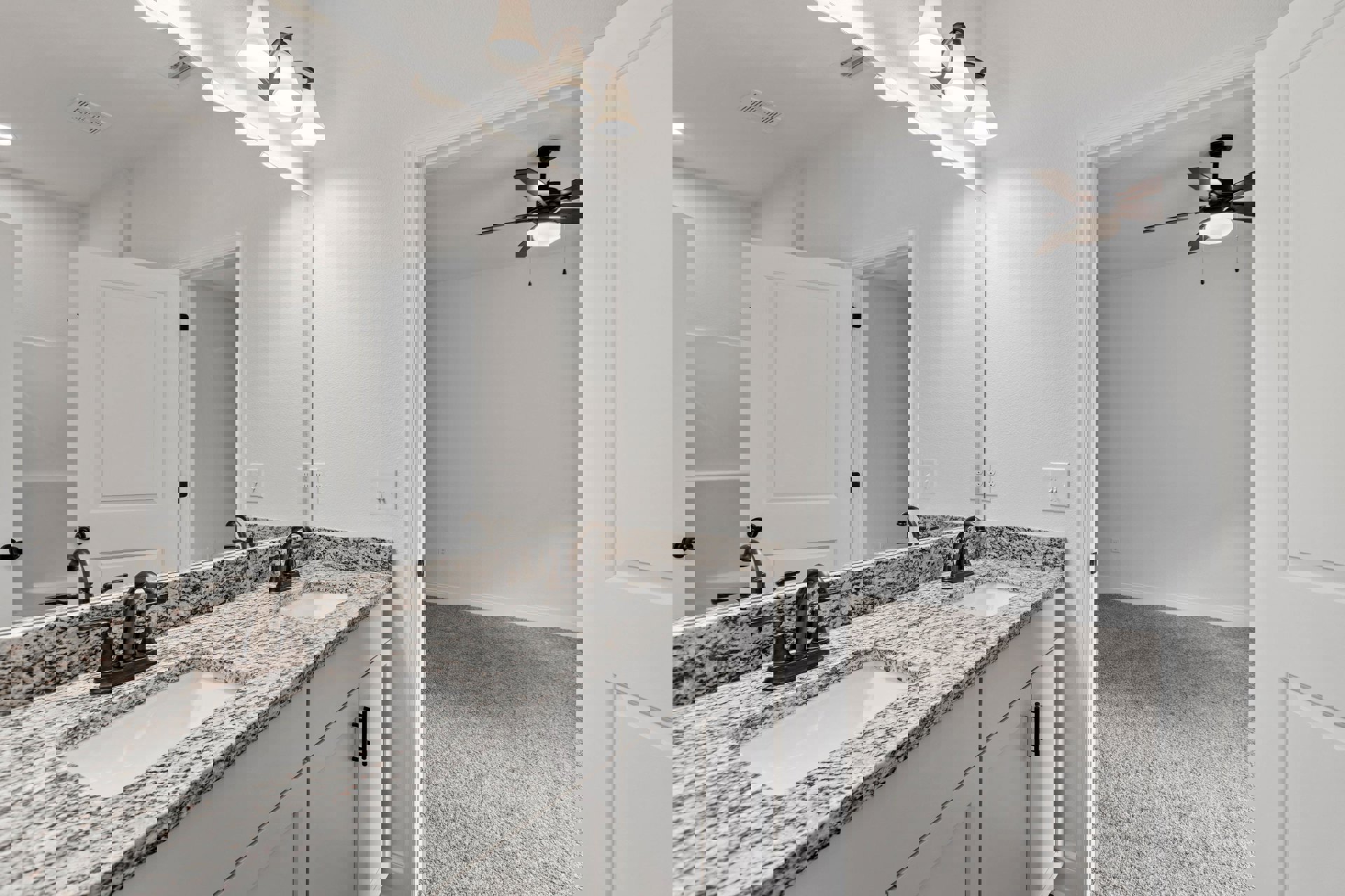 Bathroom featuring marble countertops, undermount sink with chrome faucet, white cabinetry with square panel doors, ceiling fan overhead, and neutral tile flooring