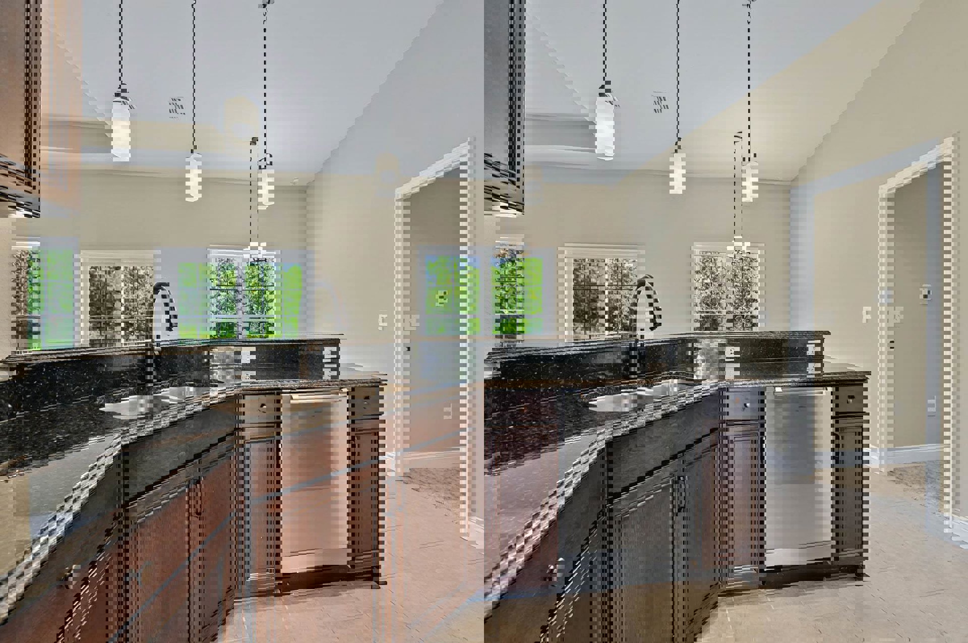 Kitchen with black countertop, stainless steel dishwasher, white cabinetry, multi-pane window, wall-mounted light fixture, and refrigerator adjacent to a white door with light