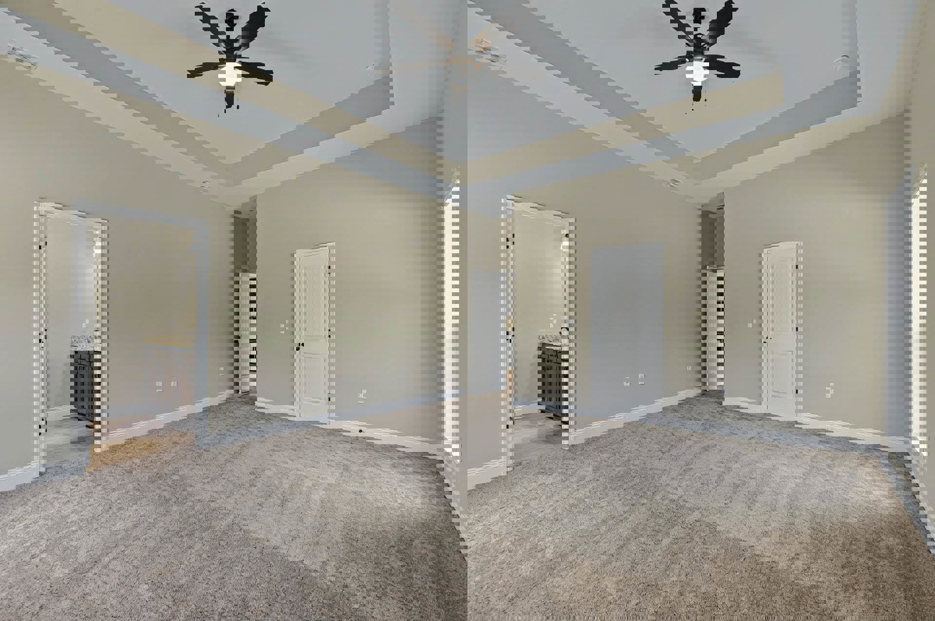 Open concept living area with carpet flooring, ceiling fan with light, adjacent kitchen featuring white cabinetry, and a white door with black hardware leading to a bathroom with