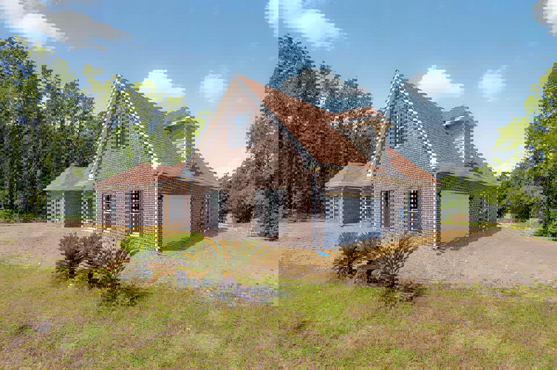 Two-story farmhouse with white siding, attached garage, concrete driveway, manicured lawn, palm tree in front yard, and windows with white frames under a partly cloudy sky