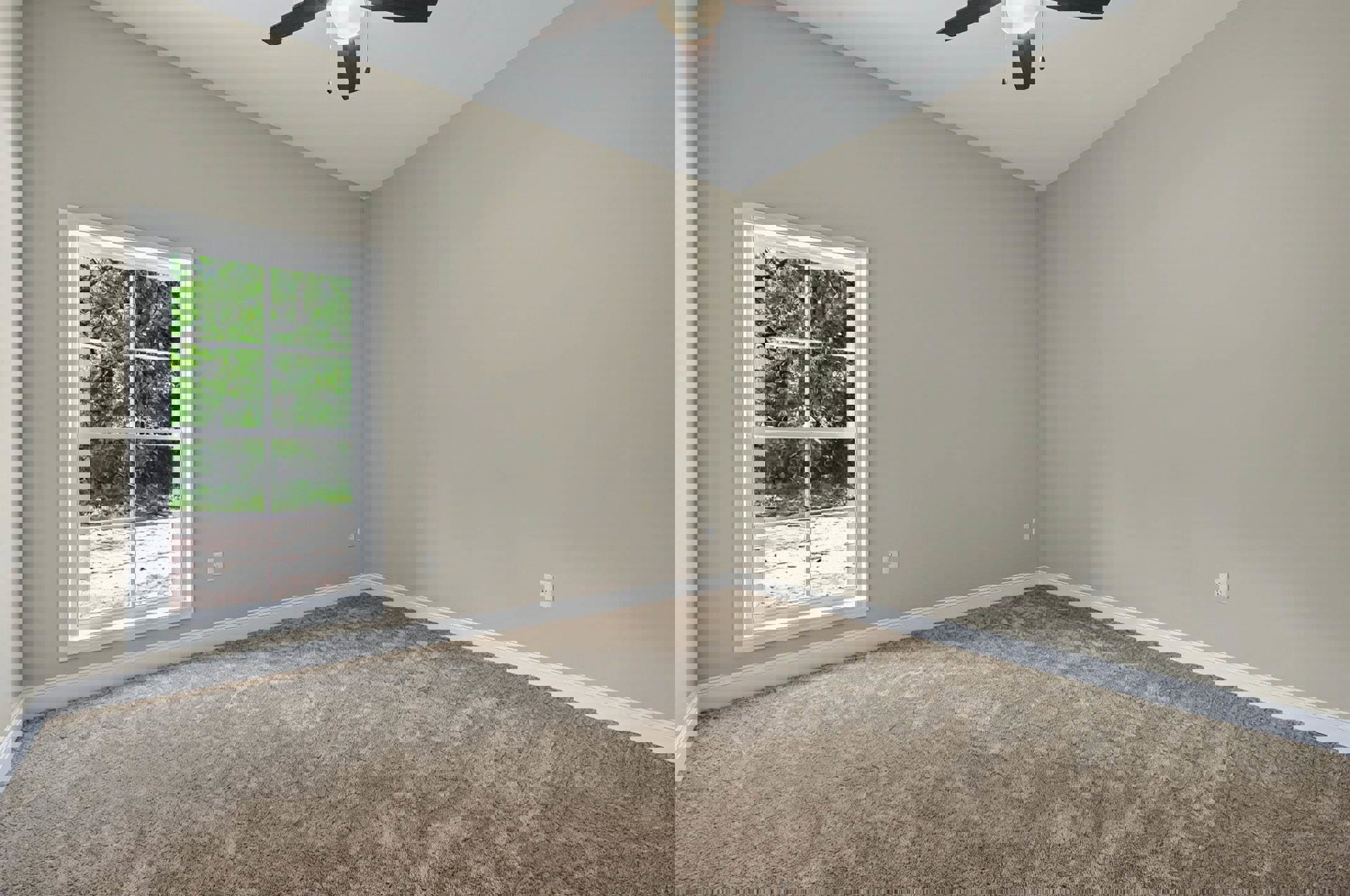 Carpeted bedroom with large multi-pane window overlooking trees, white walls, ceiling fan with light fixture