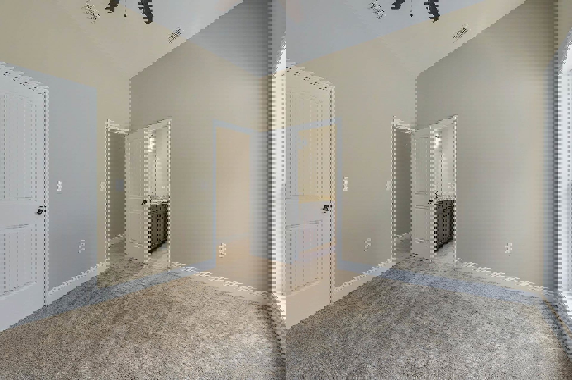 White paneled door with black knob opens to a carpeted room featuring a white sink and cabinetry against light plaster walls.