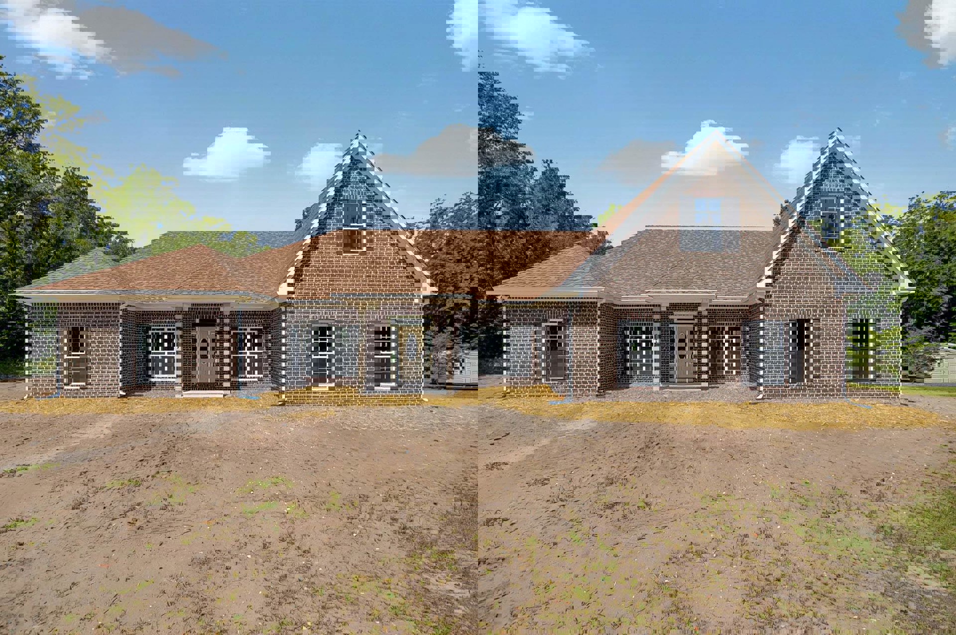 Red brick house with white front door, black shuttered windows, dirt yard, and cloudy sky