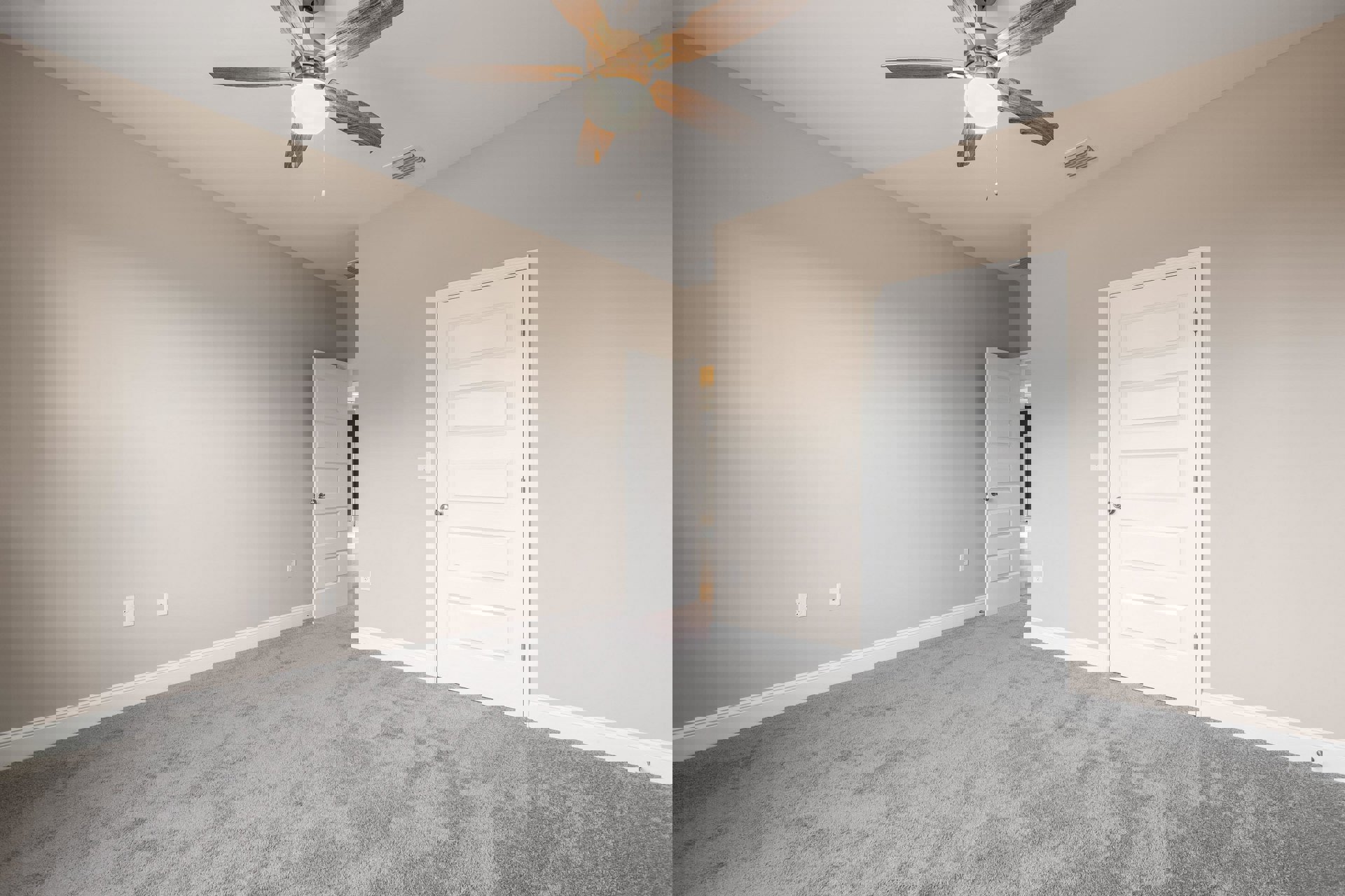 Ceiling fan with light fixture mounted on white plaster ceiling above carpeted room; open white door with silver knob leads to adjacent space; white bowl sits on wooden stand near