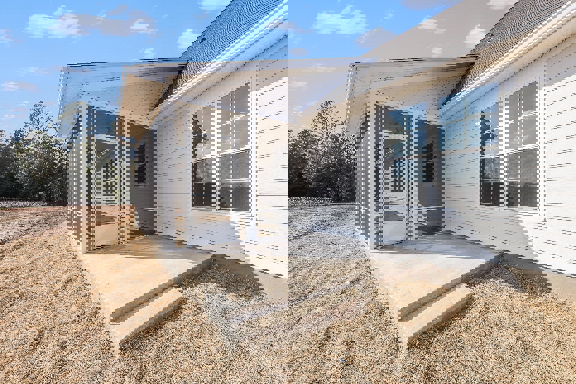 Two porches with concrete patios, white framed windows, screened window, glass door, and concrete steps leading to a garage door; light siding exterior, trees and clouds in