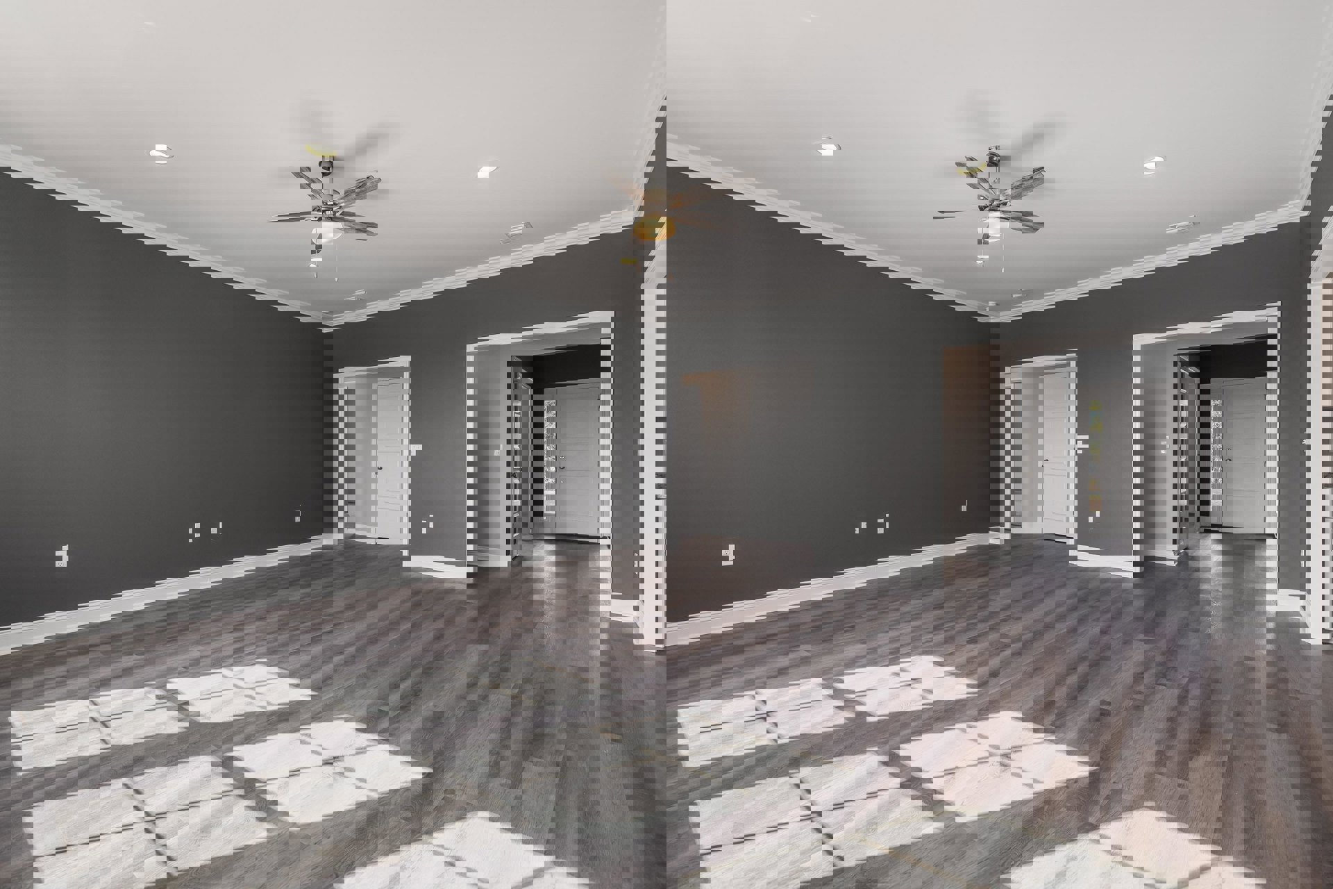 Ceiling fan with light fixture above hardwood floor, white rug, white door with glass panel and silver knob, white tile inset on wood floor, plaster walls and ceiling