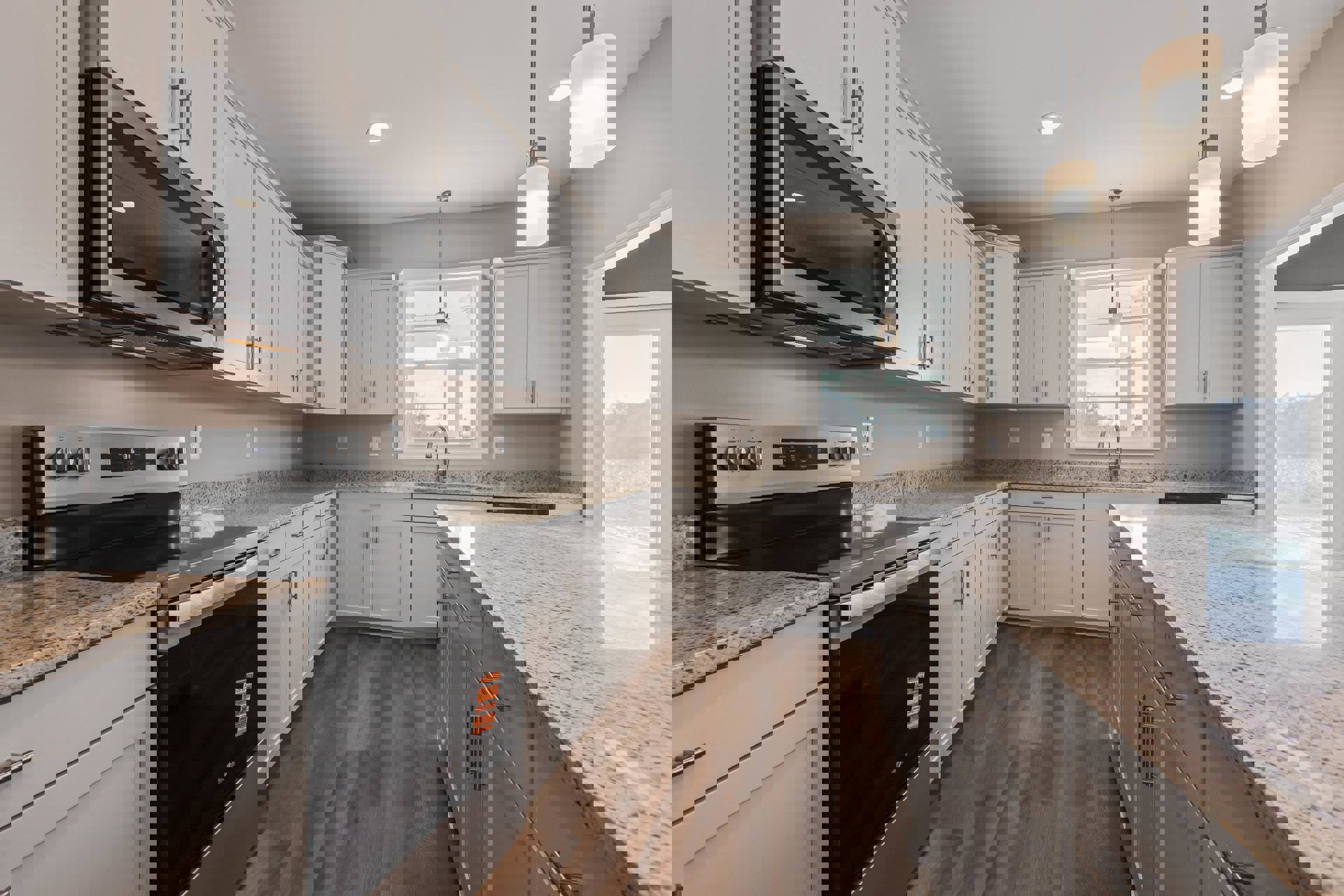 White kitchen cabinets with granite countertops, stainless steel oven and stove, built-in microwave, window above sink, recessed lighting.