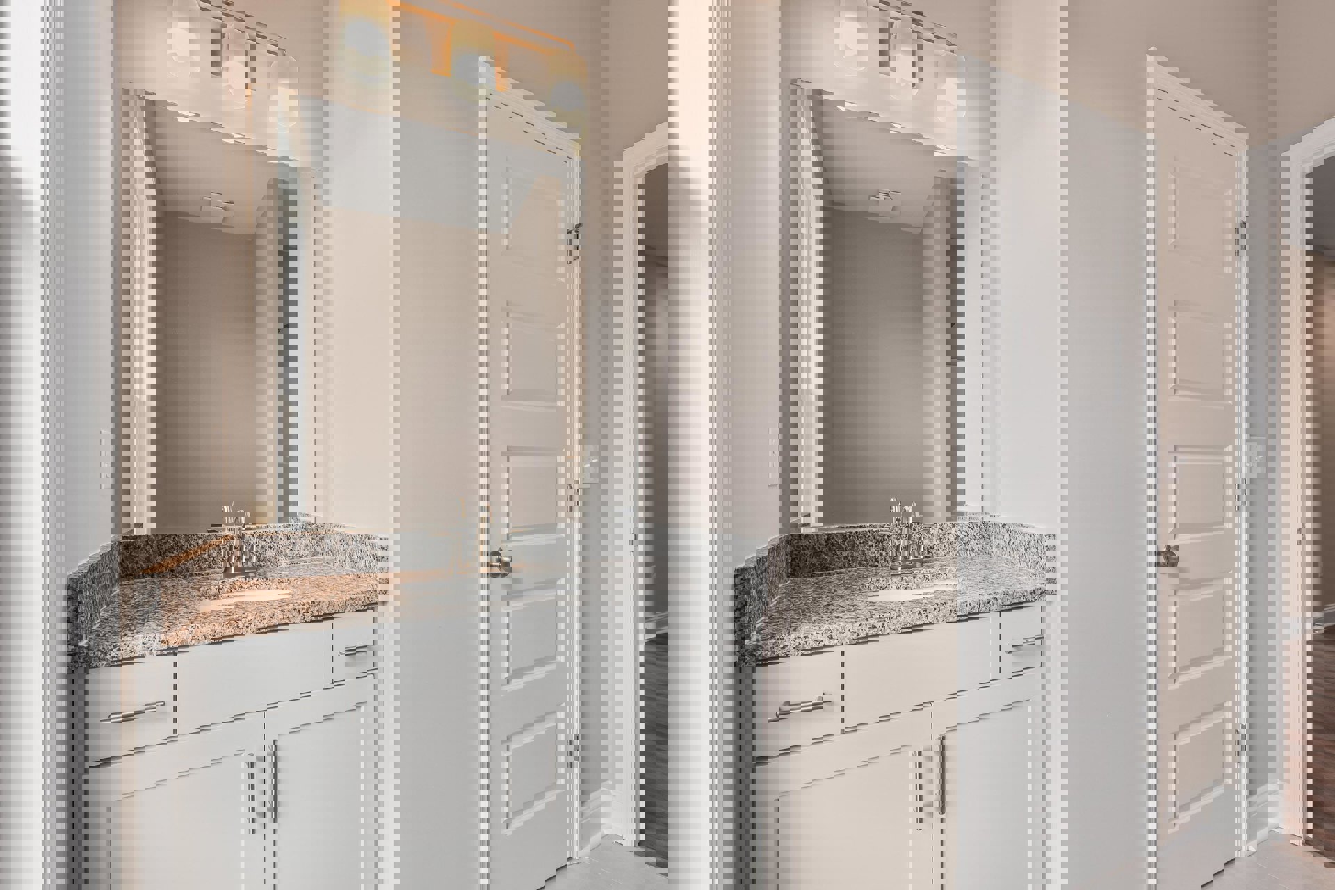 Marble bathroom countertop with undermount sink, chrome faucet, white cabinetry, large wall mirror, and white door with silver knob