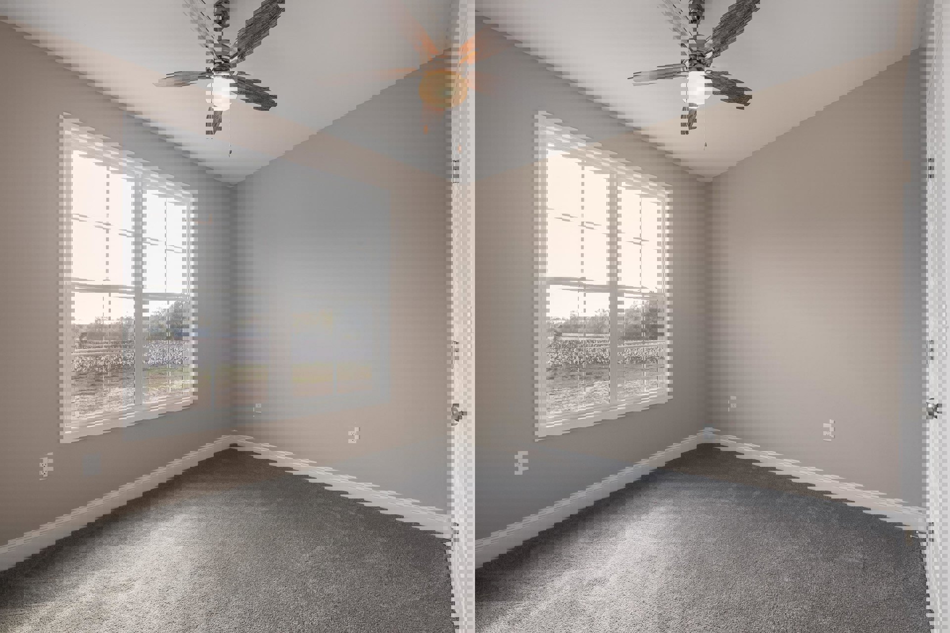 Bedroom with grey carpet, white walls, ceiling fan with light fixture, large window overlooking grassy field, crown molding along ceiling edges