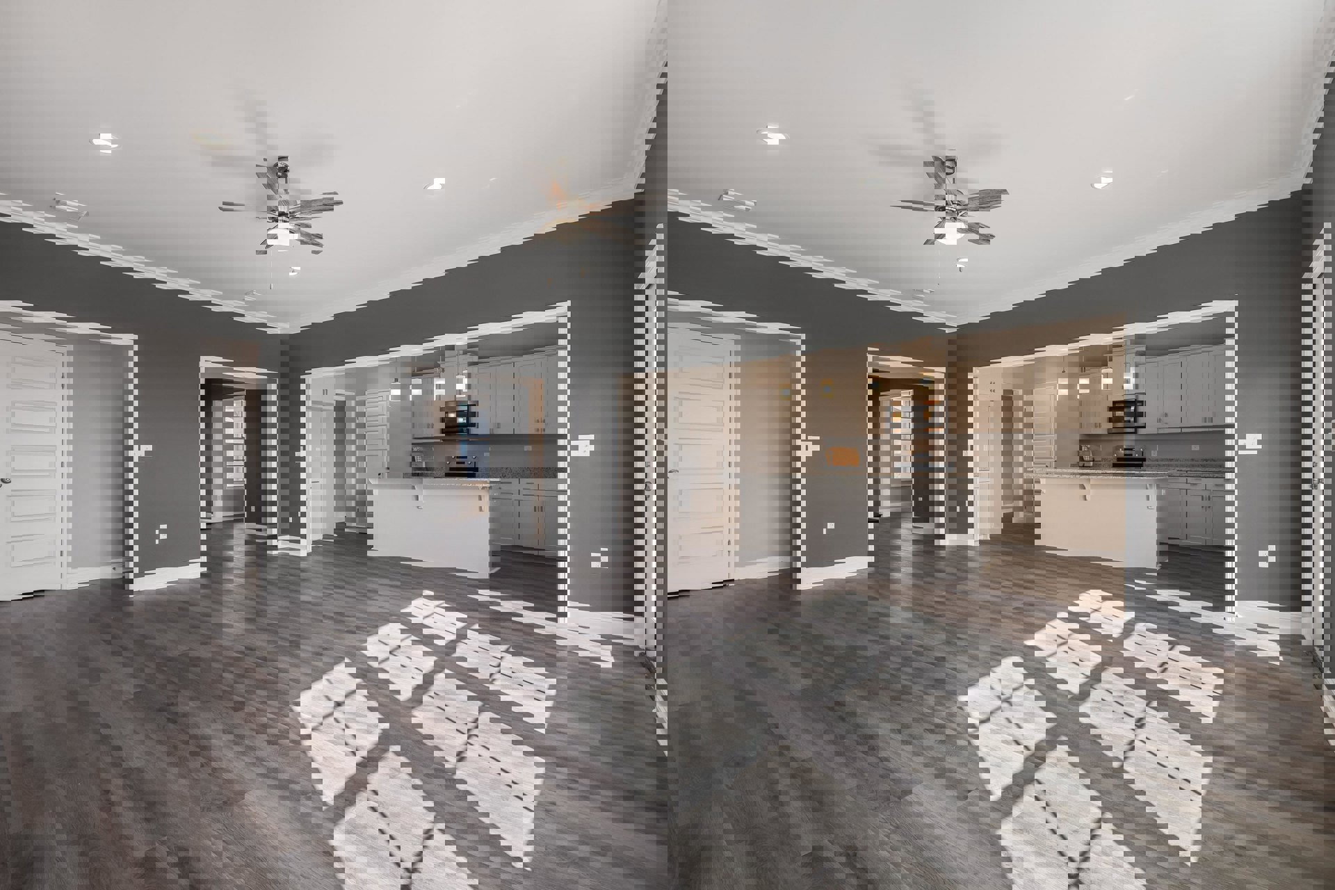 Open concept kitchen and dining area with wood flooring, ceiling fan with light, white door with silver knob, large windows, and neutral walls