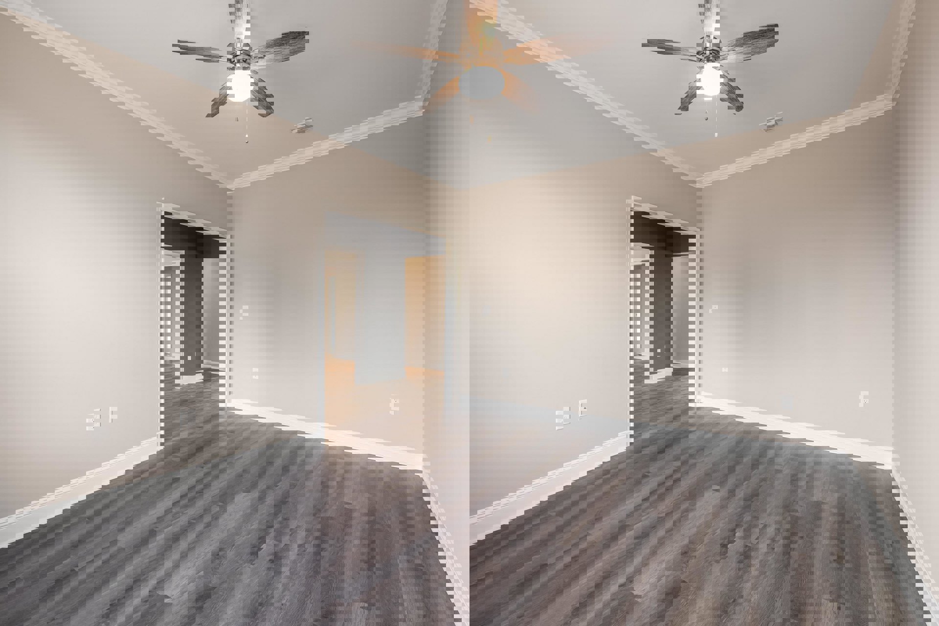 Ceiling fan with light fixture mounted on white ceiling, hardwood flooring with white baseboard trim, gray painted walls, hallway visible in background