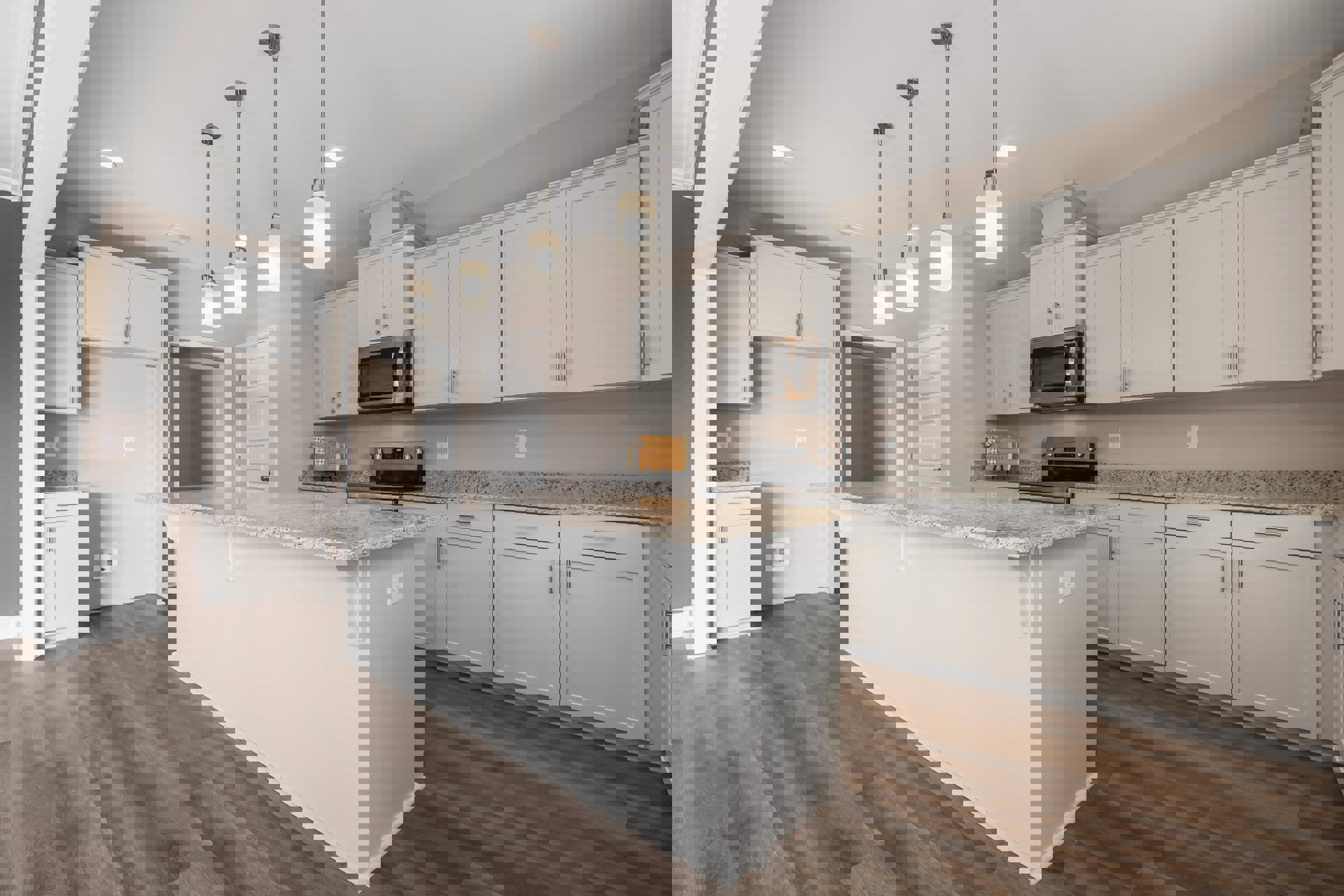 Marble kitchen island with wood flooring, white cabinetry, built-in microwave, wall-mounted light fixture, and close-up of a white door