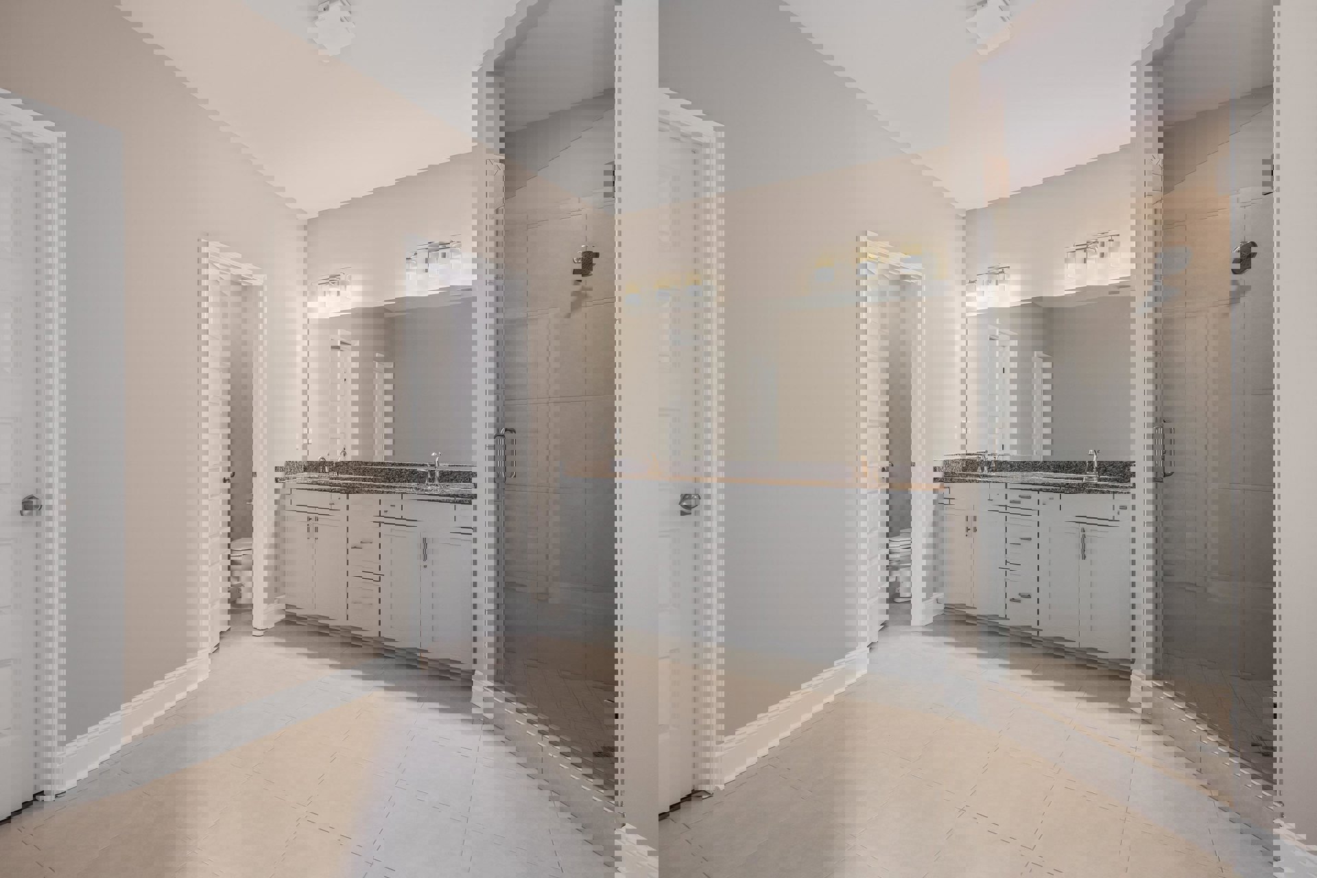 White bathroom with glass shower enclosure, granite countertop on white cabinets, silver hardware, white tile floor, and modern toilet.