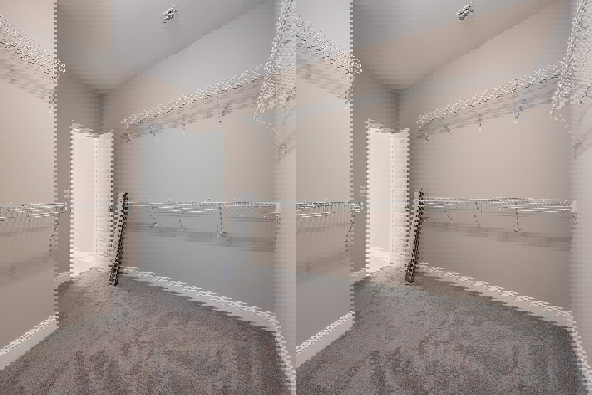 Carpeted room with white shelving and hooks, white door with silver knob and frame, pile of books on floor, gym machine in foreground, plaster walls, ceiling, and tile accents