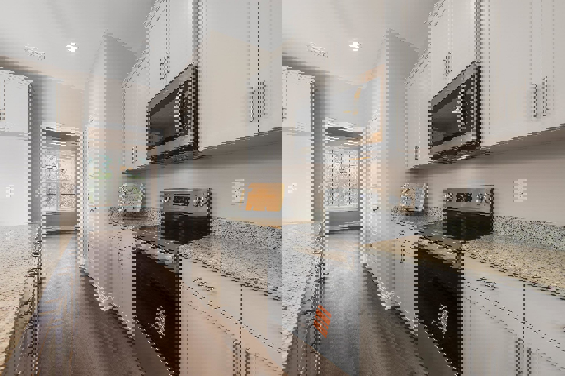 White shaker cabinets, stainless steel microwave mounted above stove, light quartz countertops, wood cutting board with ribbon, tile backsplash, electrical outlet on wall