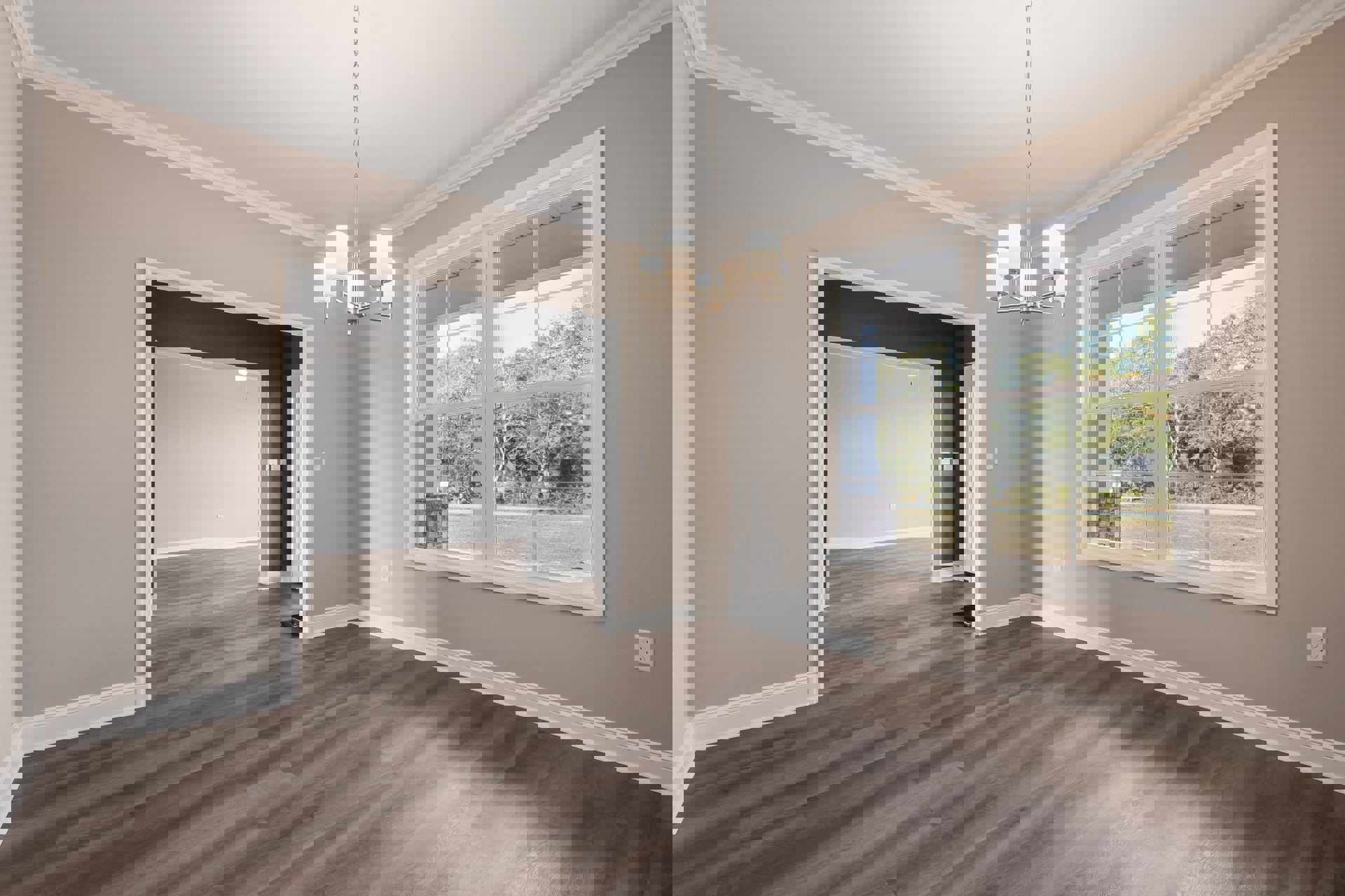 Wood flooring in a room with white walls, black ceiling, open door, large window overlooking trees, and a chandelier with white shades.