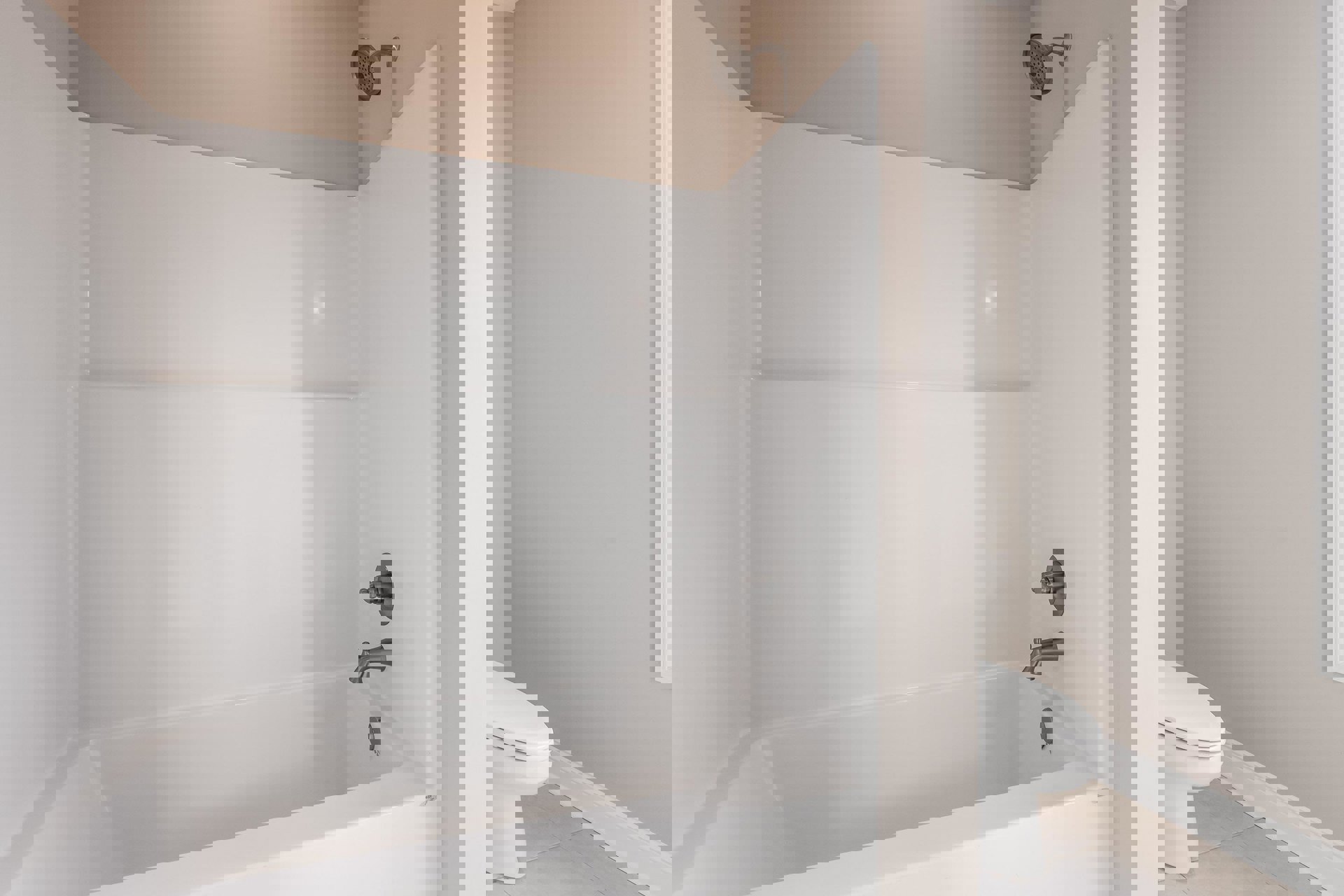 Freestanding white bathtub with chrome faucet, white tile walls, and adjacent shower head in modern bathroom