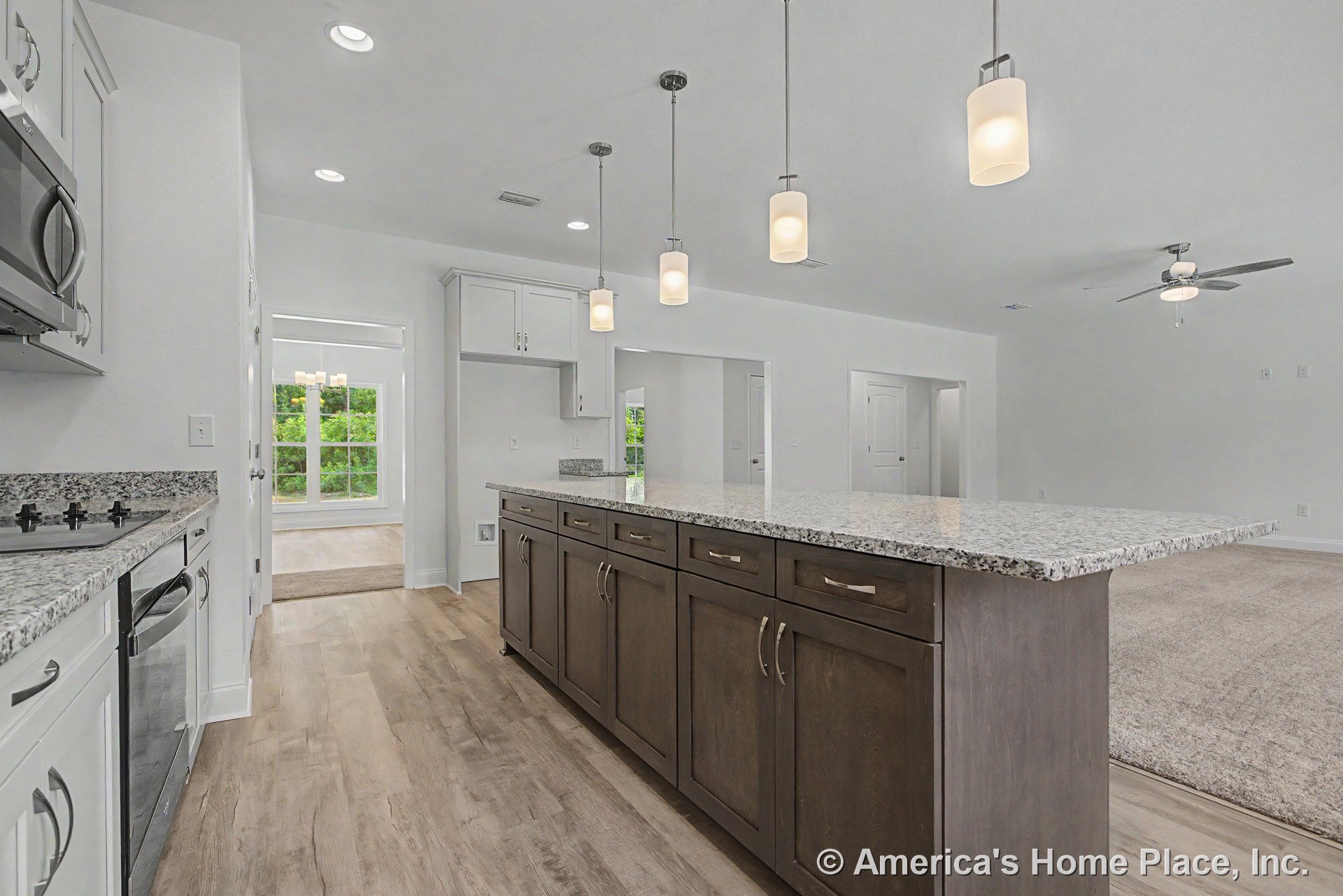 Granite island with dark wood cabinetry, pendant lights above, open floor plan with wood-look flooring, white upper cabinets, stainless appliances, window, ceiling fan, and