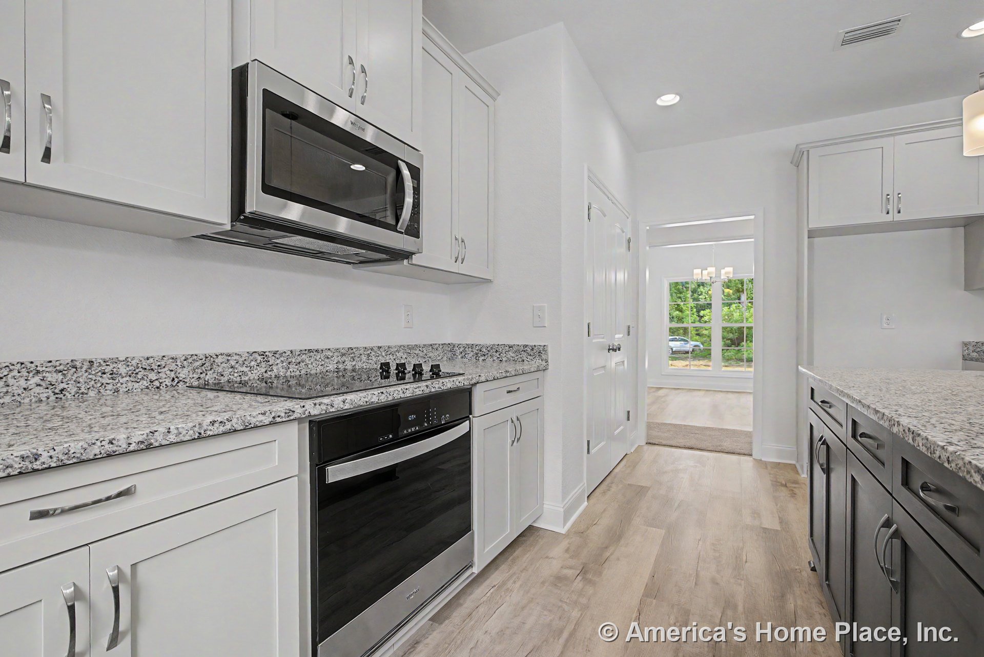 Granite countertops with white shaker upper cabinets and gray lower cabinets, stainless steel appliances including built-in microwave, electric cooktop, and dishwasher, recessed