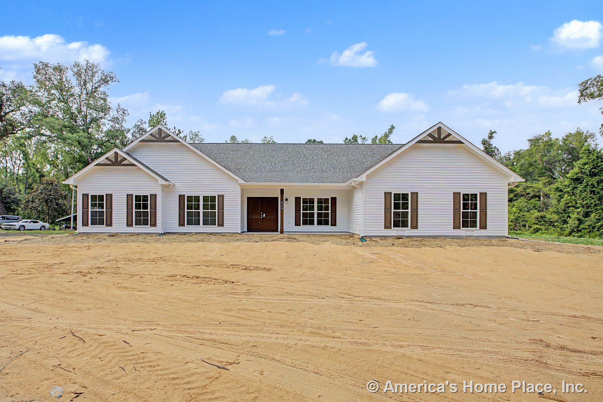 White siding single-story home with gable roof, covered front porch, double front doors, multiple large windows framed by brown shutters, and contrasting trim.