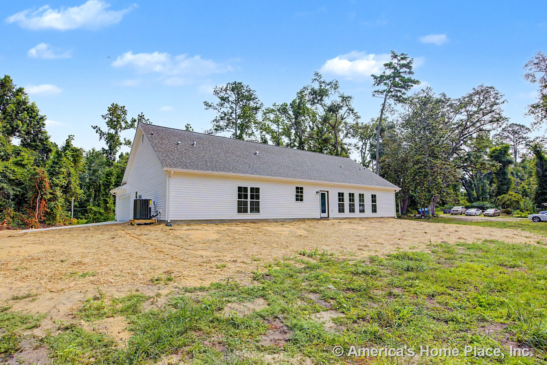 White vinyl siding exterior with gable shingle roof, several double-hung windows, single glass-paneled exterior door, outdoor HVAC unit, and unfinished yard.