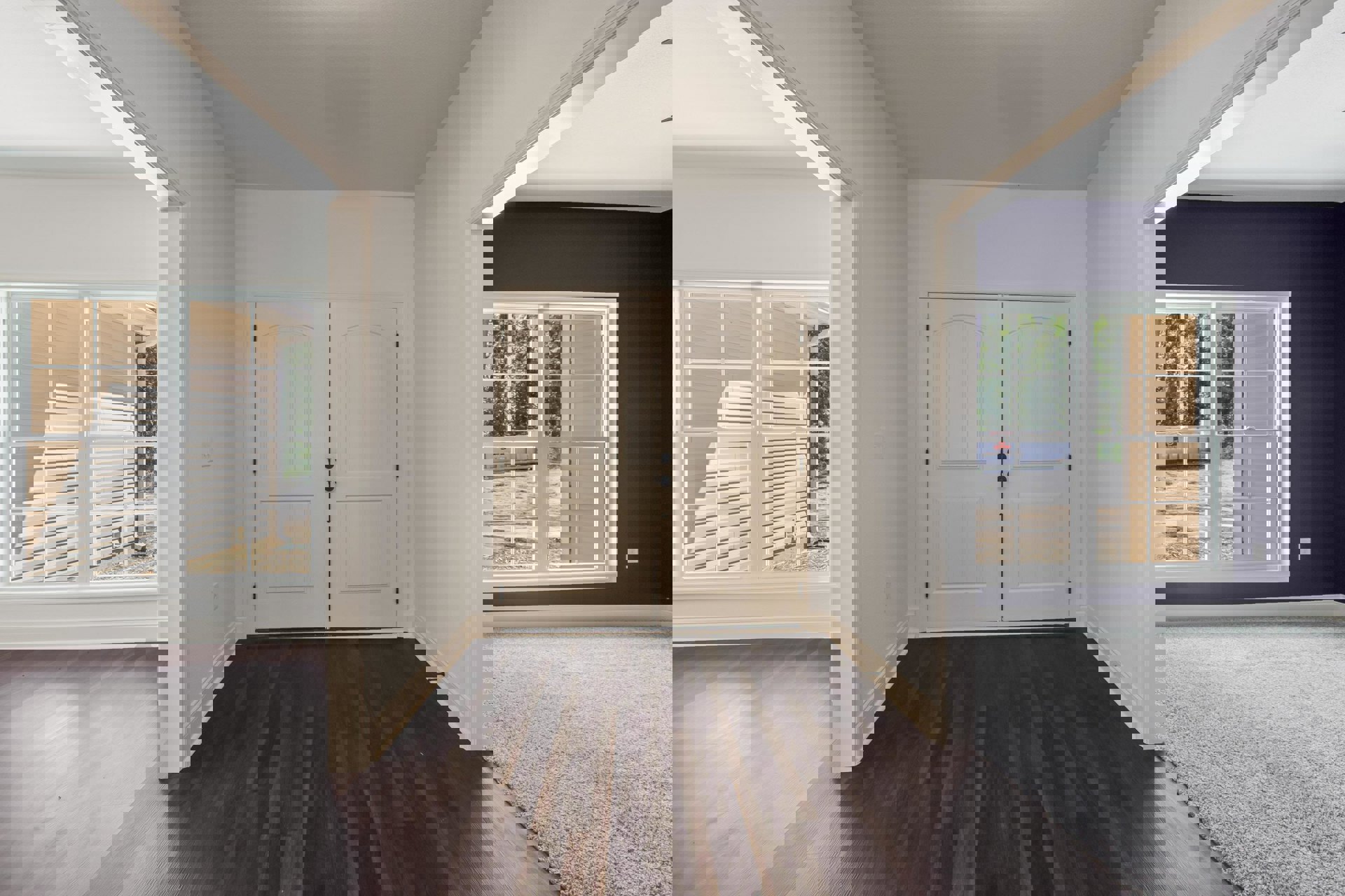 Hallway featuring double white doors with silver door knobs, hardwood flooring, white walls, and window trim