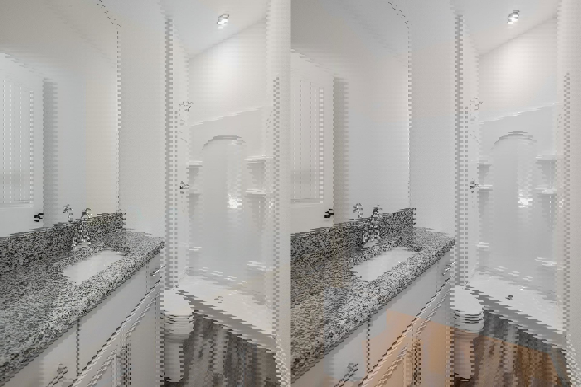 Bathroom with white tile shower, chrome showerhead, white toilet, light wood vanity with integrated sink, stone countertop, and flat panel cabinetry