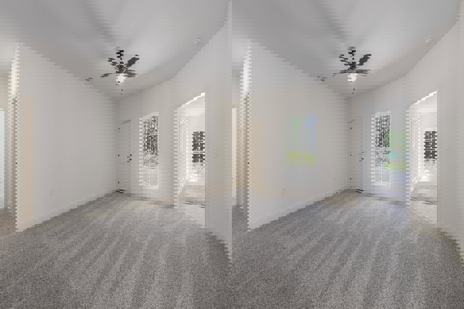 Carpeted bedroom with white walls, ceiling fan and light fixture, white door with black hardware, window overlooking trees