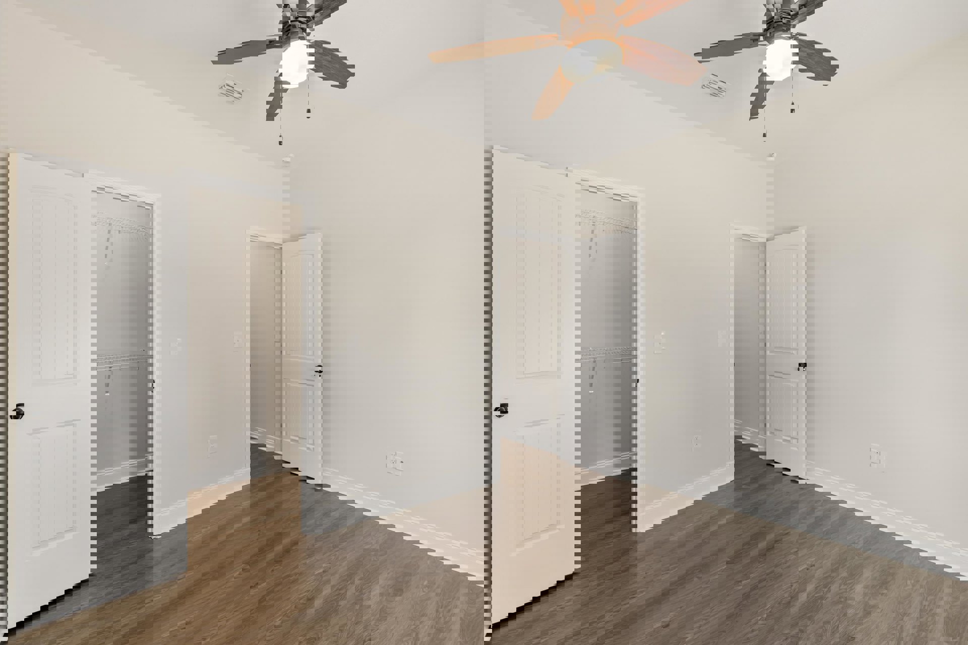 Bedroom with wood flooring, white walls, ceiling fan with light, white closet door featuring black handle