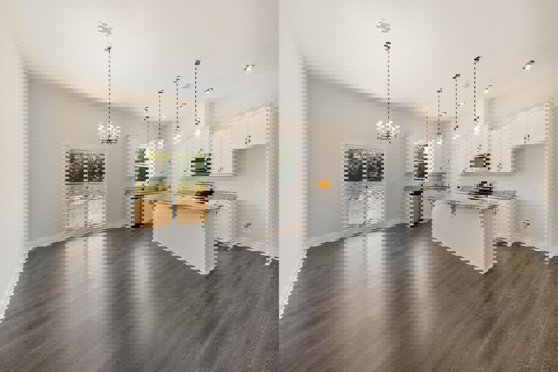 Spacious kitchen featuring a large central island, wood flooring, white cabinetry, stainless steel appliances including an open microwave and visible dishwasher, sliding glass door