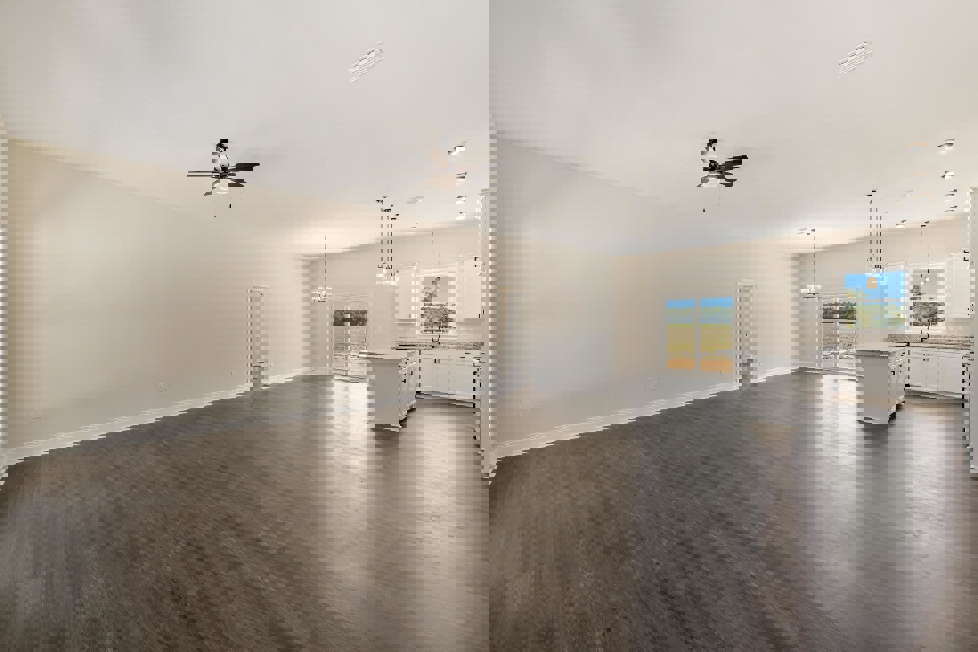 Spacious empty room with light hardwood flooring, white walls, ceiling fan with light fixture, large window overlooking grassy field