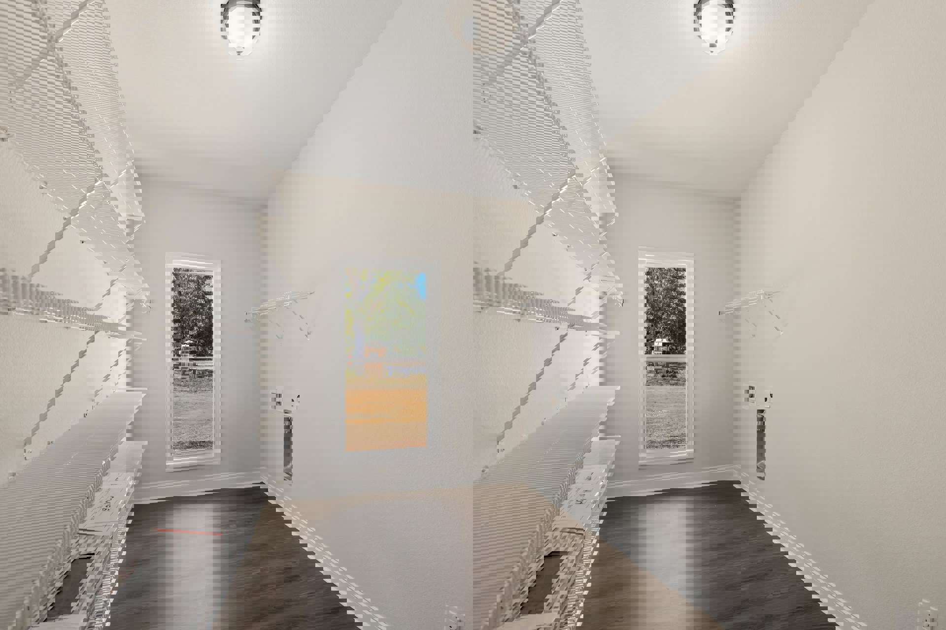 Spacious empty room featuring built-in white shelves, large window with natural light, smooth plaster walls, light wood flooring, and recessed ceiling fixture