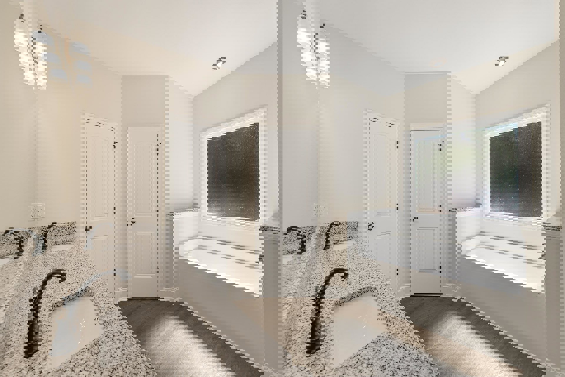 Bathroom featuring marble countertop with black faucet, freestanding bathtub, white sink with black speckled surface, white door with black handle, and wall-mounted blackboard in