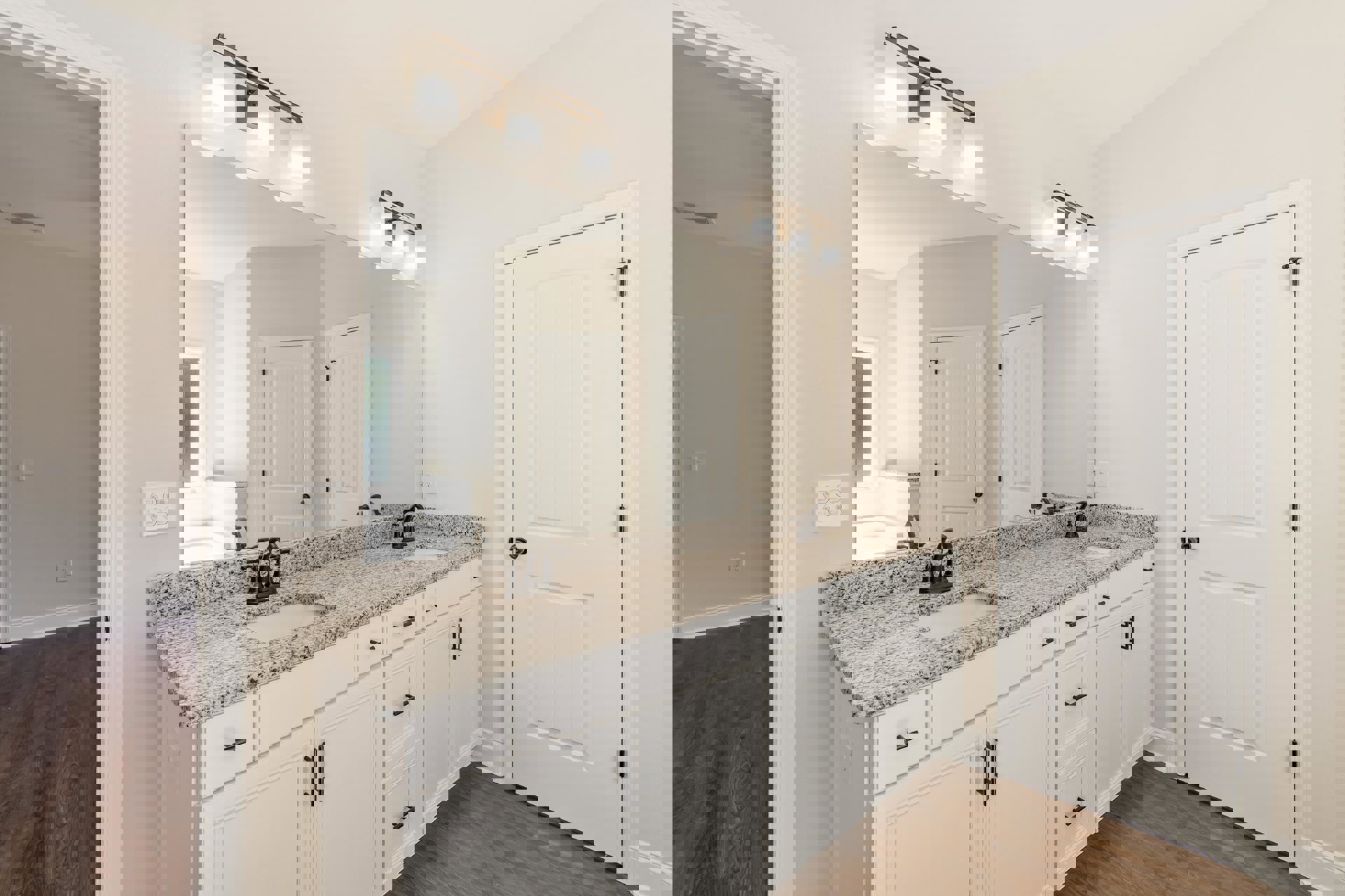 Bathroom featuring a large mirror above a marble countertop with a black faucet, wood flooring, white door with black knobs, wall outlet, and a light fixture with a white shade.