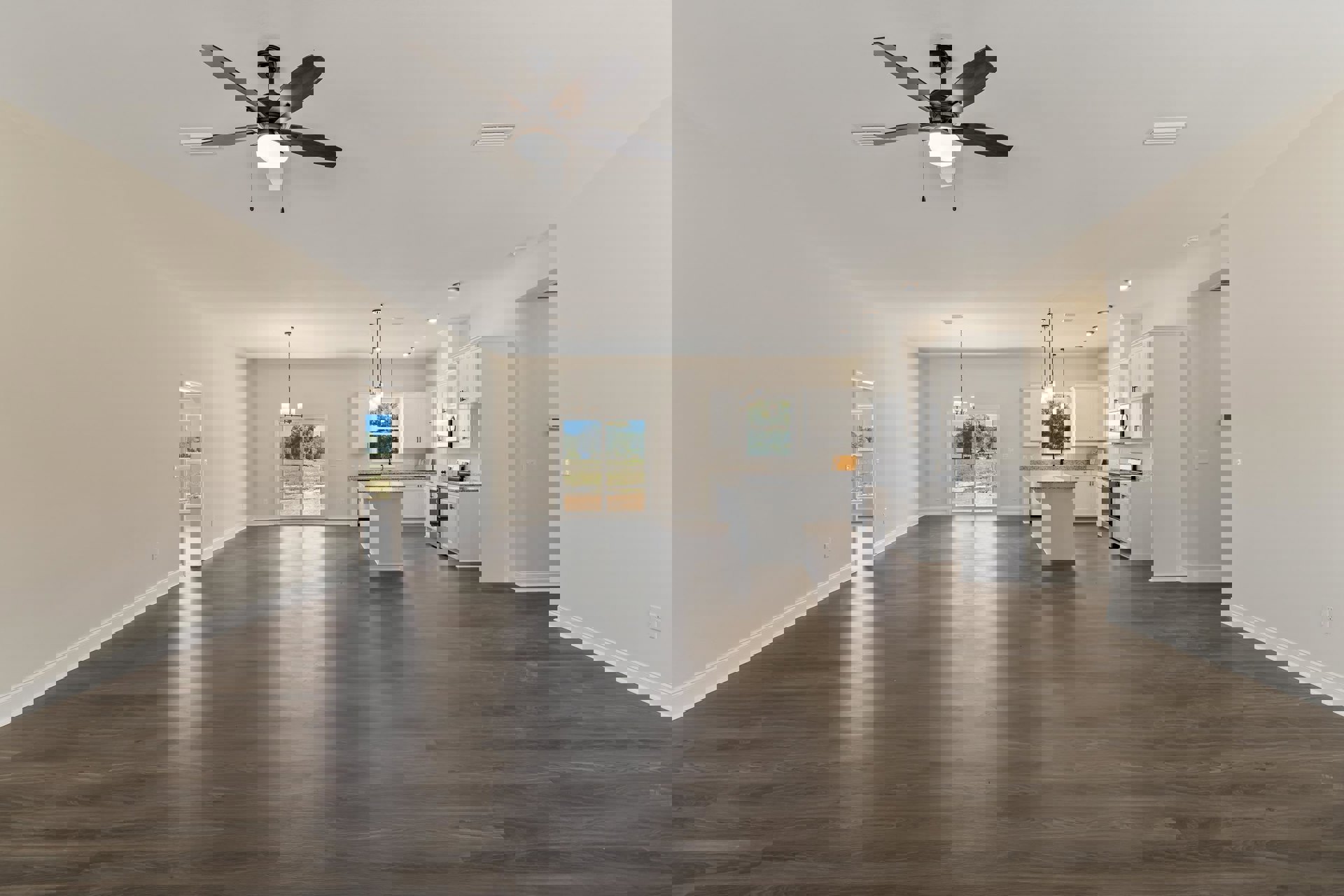 Spacious open floor plan featuring light wood flooring, a ceiling fan with integrated light, white kitchen cabinetry with a white countertop, large windows overlooking a grassy