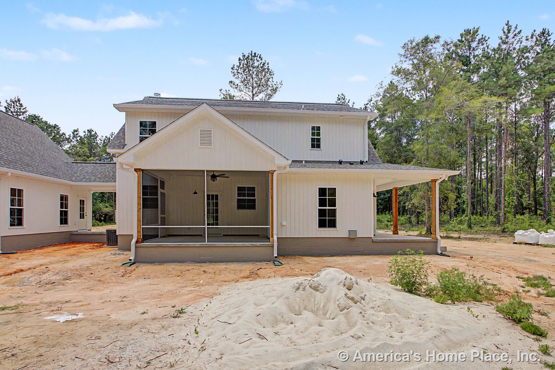 Covered rear porch with wood columns, ceiling fan, white vertical siding, multiple windows, gable roof, outdoor lighting, and decorative trim on two-story home.