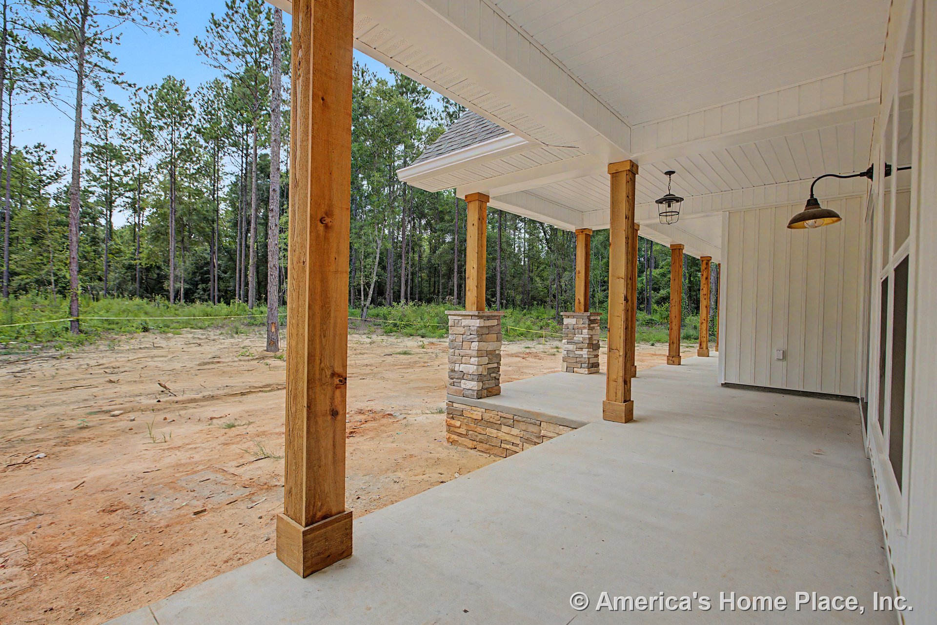 Covered front porch with wood columns on stone bases, concrete flooring, white beadboard ceiling, exterior wall sconce, and hanging porch light.