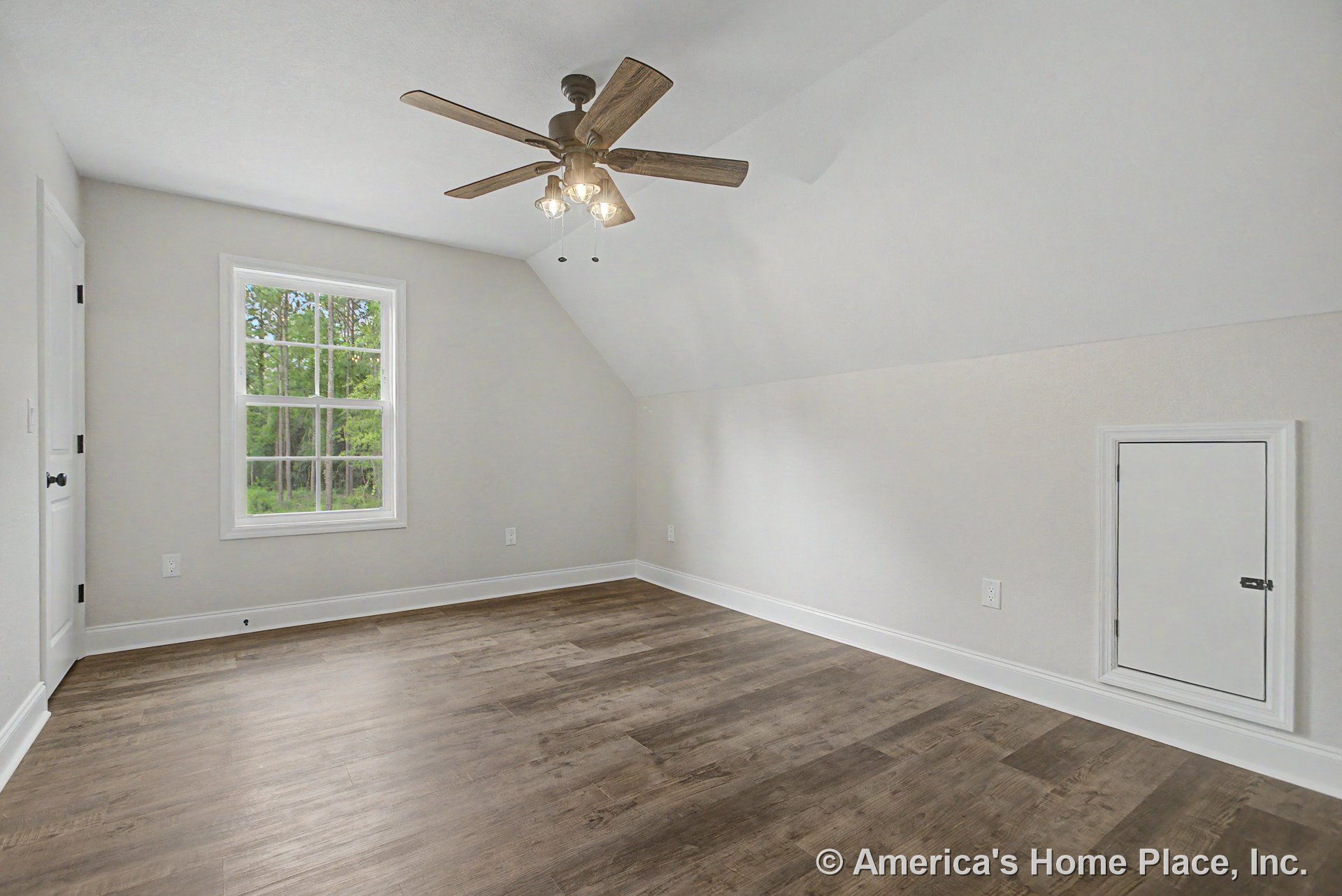 Finished attic room with wood-look plank flooring, sloped ceiling, ceiling fan and light fixture, single divided-pane window, white trim and baseboards, small access door in wall
