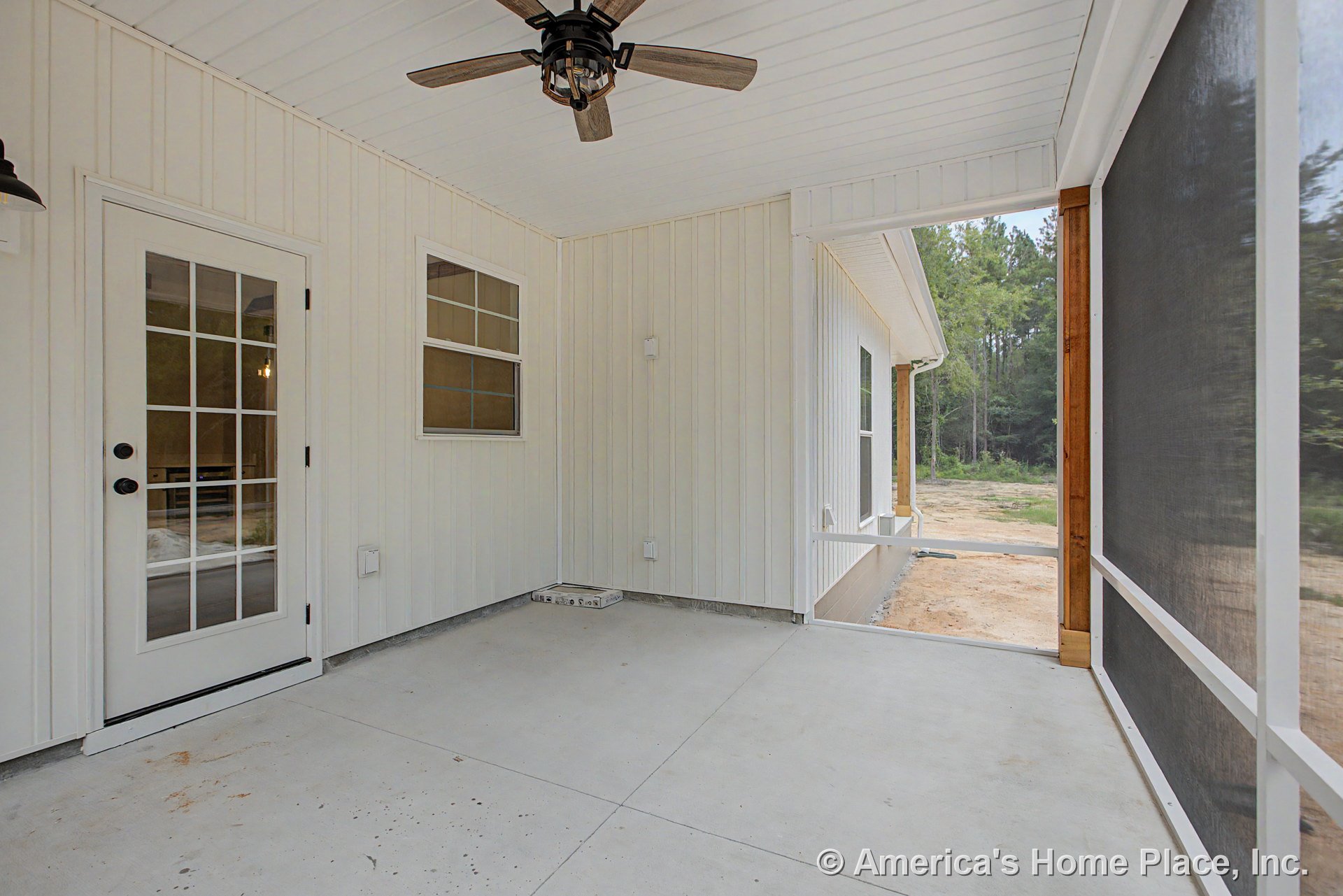Screened porch with concrete floor, white vertical wall siding, ceiling fan with light, multi-pane glass door, and double window unit.