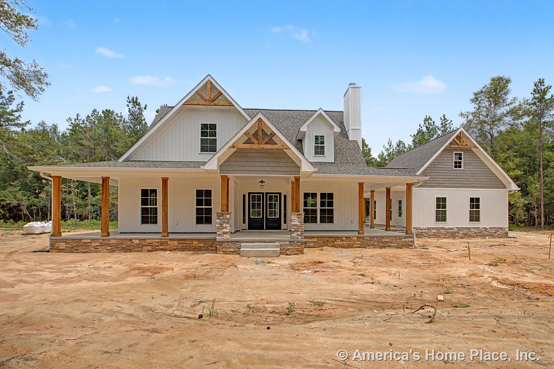 Large wraparound porch with stone column bases and wood posts, board and batten siding, multiple gabled rooflines, double front doors, and prominent windows; covered entry with
