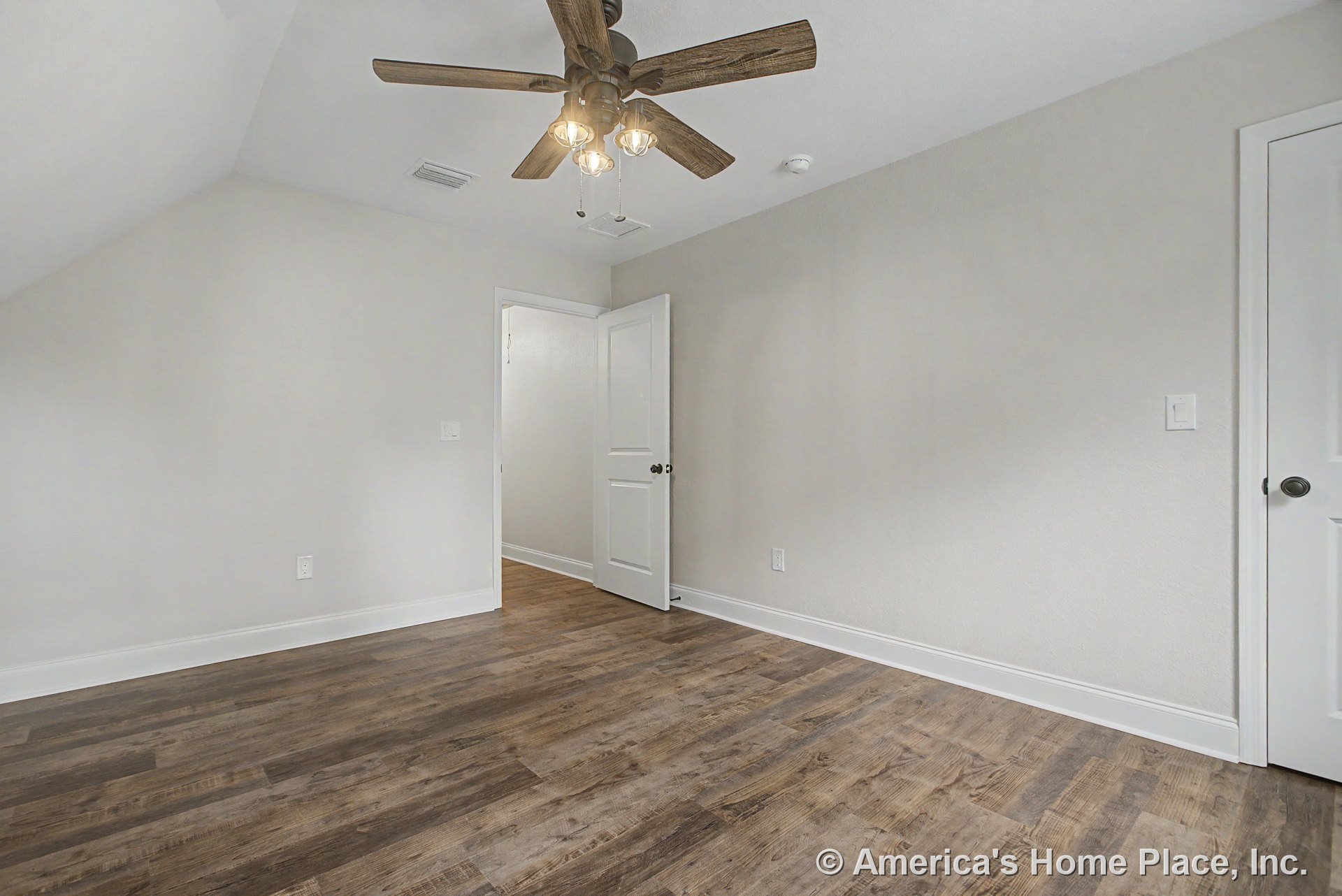 Bedroom with wood-look plank flooring, light gray painted walls, white baseboards, ceiling fan with built-in lights, panel doors, and a flush ceiling vent.