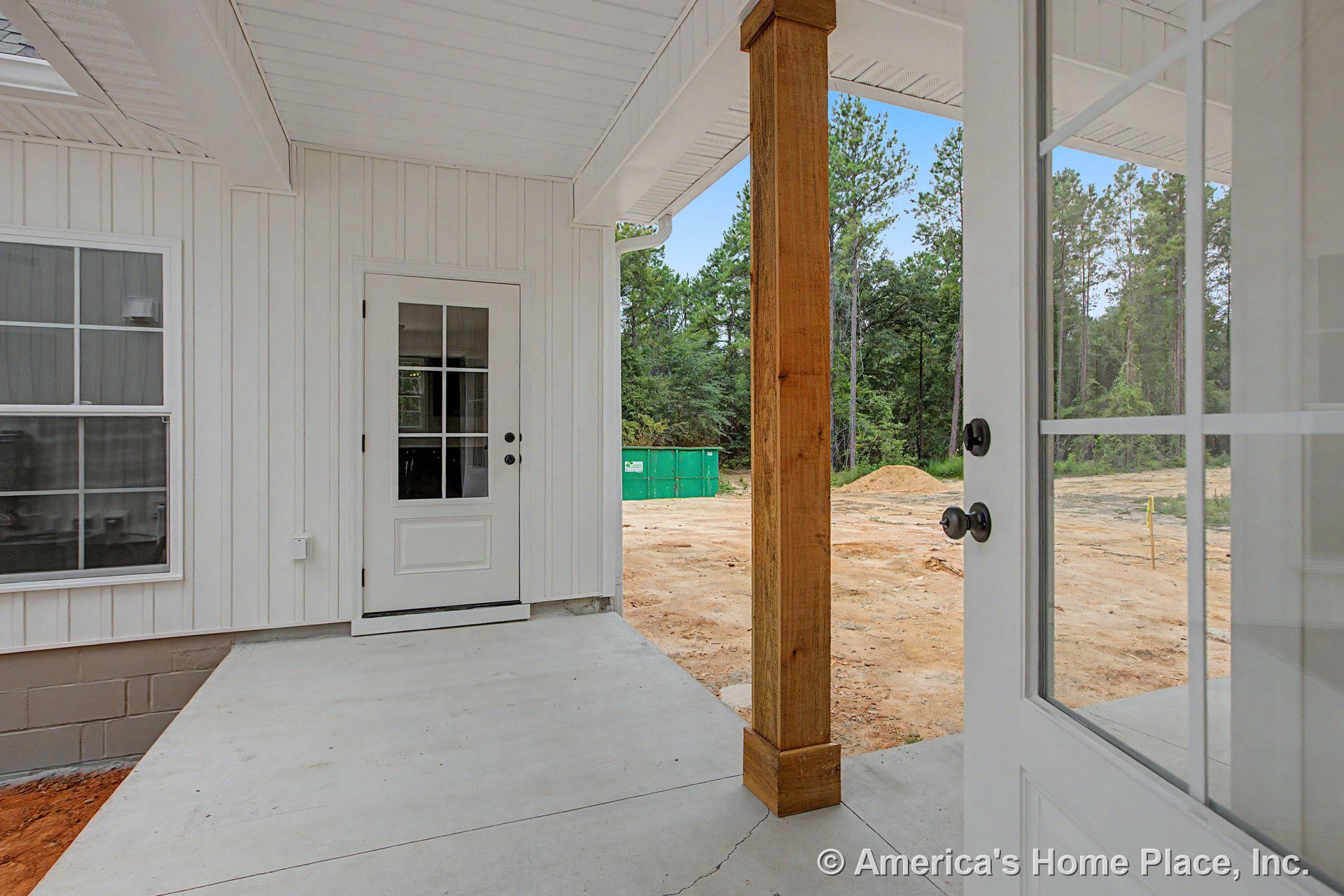 Covered porch with vertical white siding, concrete flooring, wood support column, multi-pane exterior doors, double-hung window, and finished ceiling with trim.