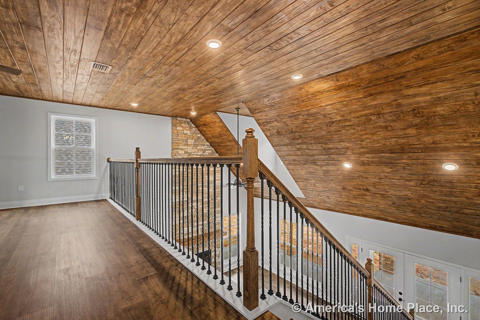 Stair landing with wood plank ceiling, recessed lighting, stone accent wall, iron and wood railing, large window with trim, double glass doors, and hardwood flooring.