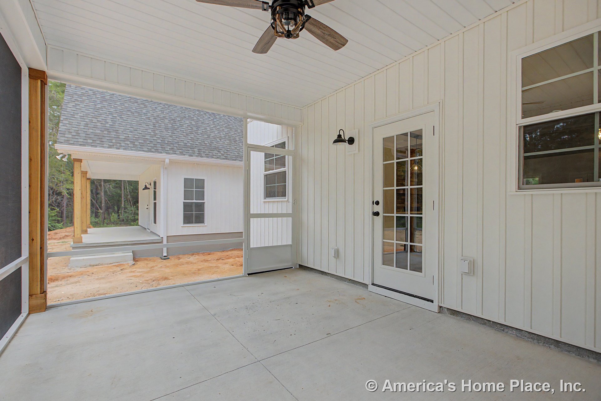 Screened porch with concrete flooring, white vertical siding, ceiling fan with light, glass paneled exterior door, wall-mounted exterior light, and covered entry.