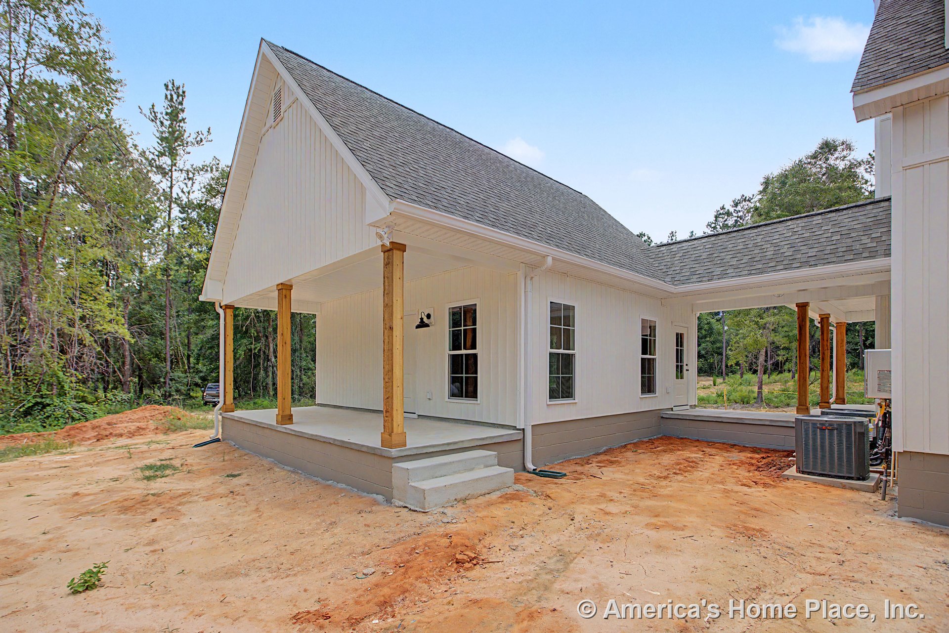 Covered front porch with wood support columns, white vertical siding, concrete steps, multiple double-hung windows, gray shingle roof, white trim, outdoor lighting fixtures