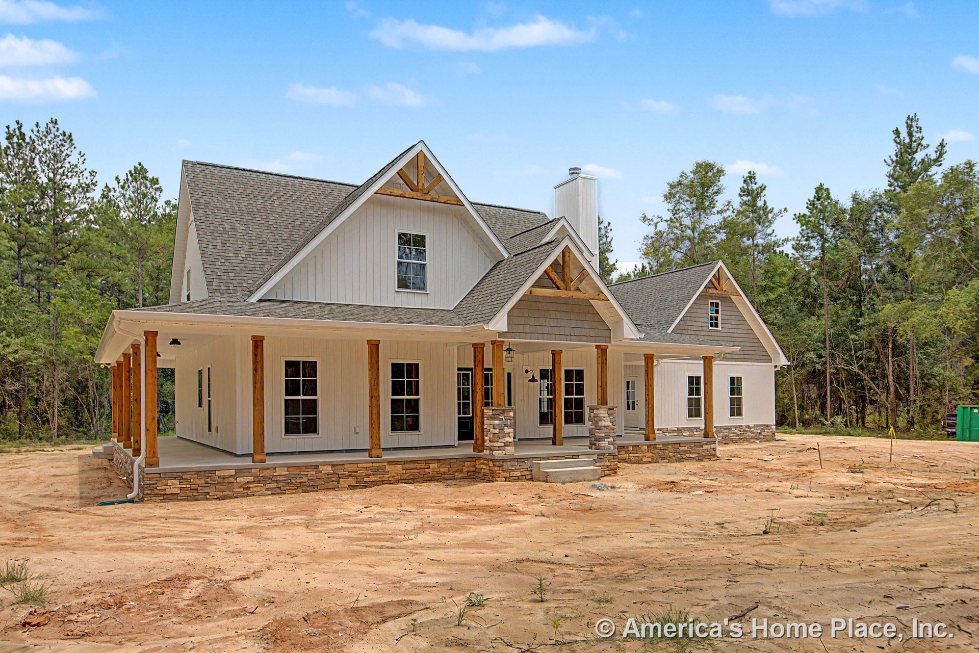 Large covered front porch with stone column bases and wooden support posts, board and batten siding, multiple gabled roof accents, trimmed windows, permanent lighting, and